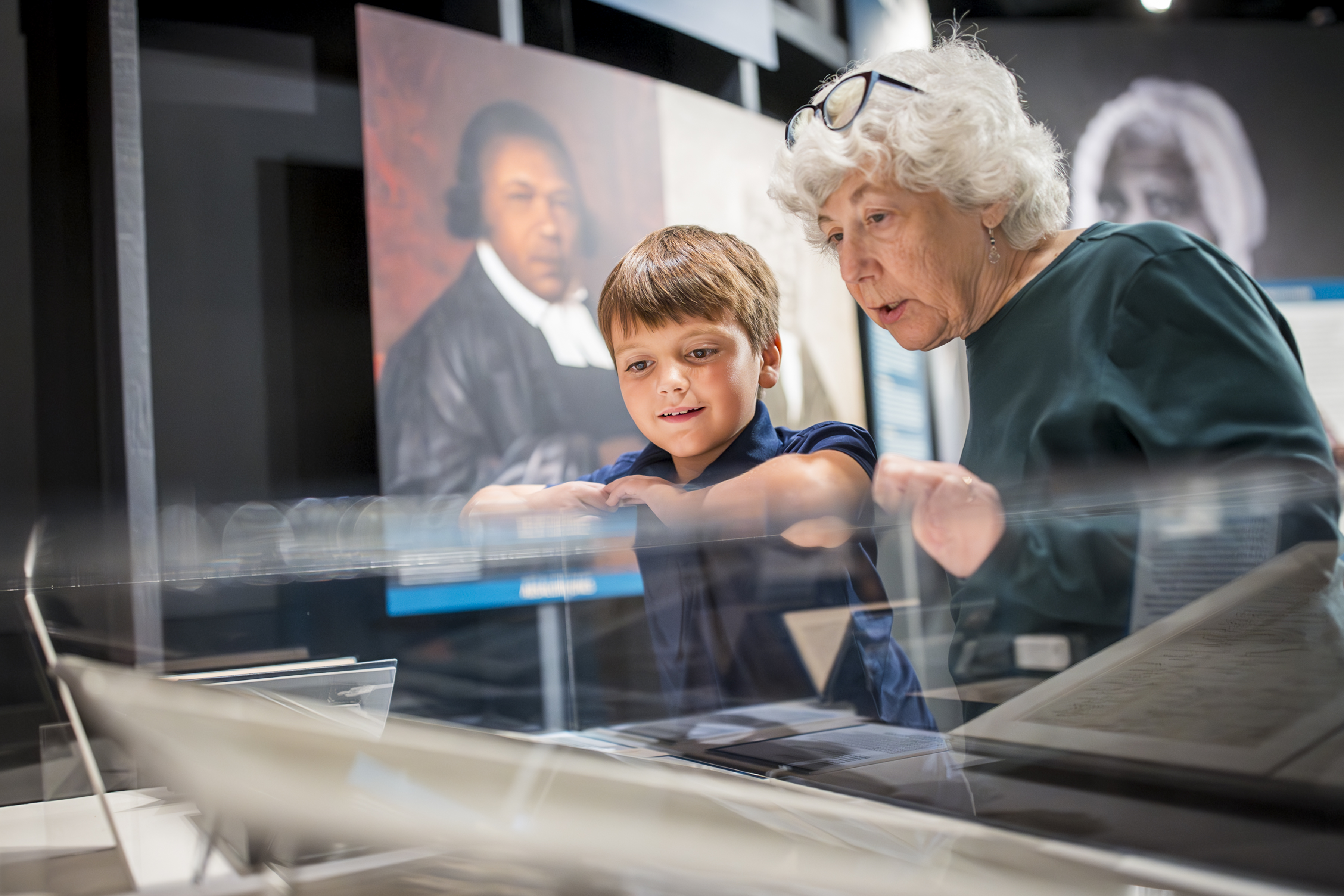 A child and a woman look at objects in a glass case