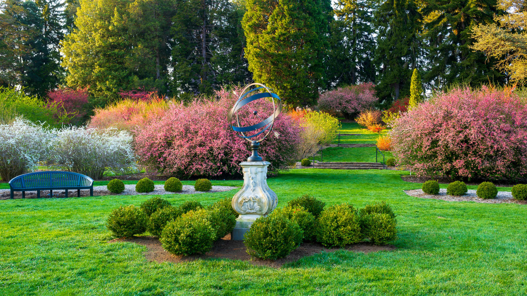 This image shows a sculture in the middle of a field and garden.