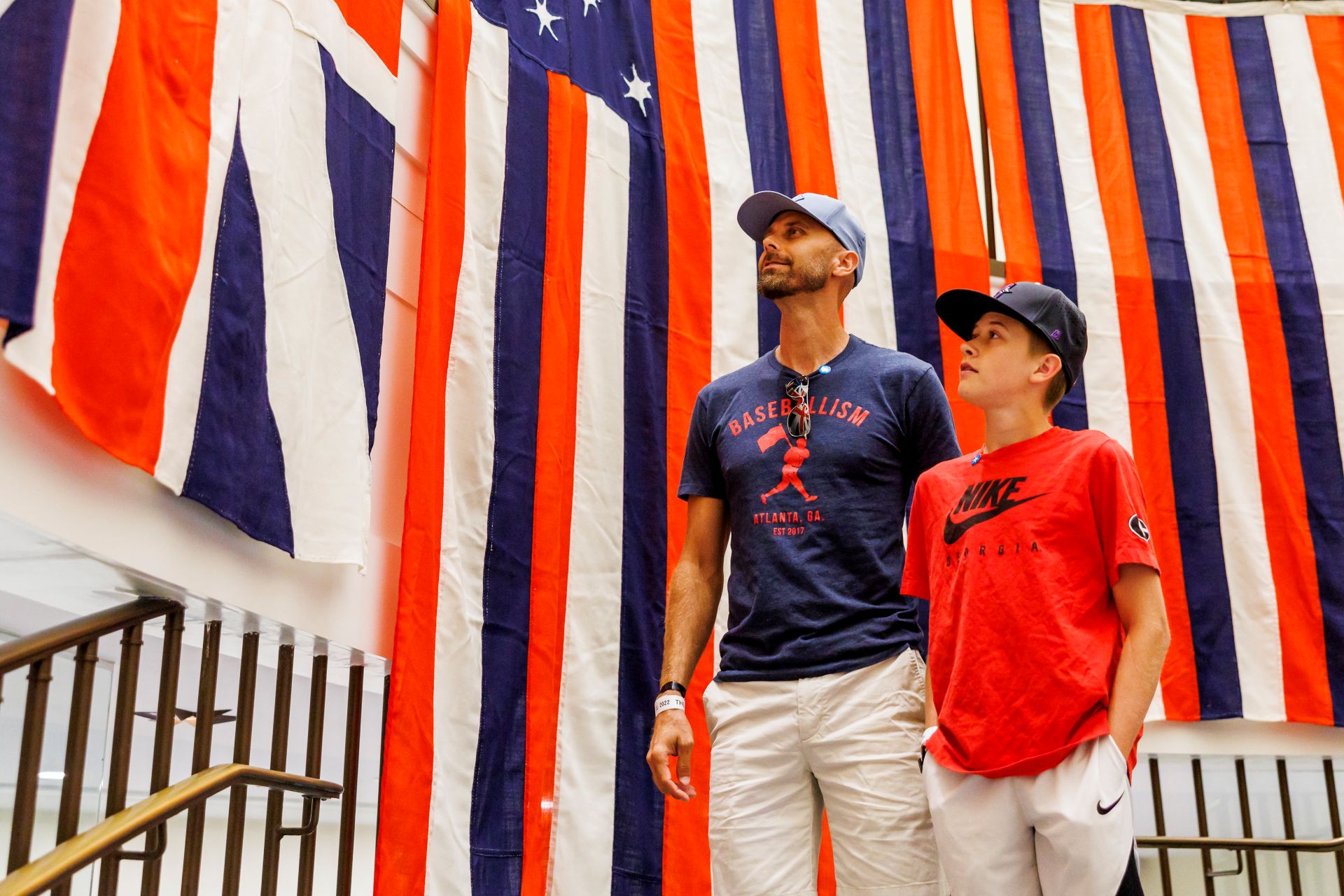 A man and child stand in front of hanging red, white, and blue striped flags