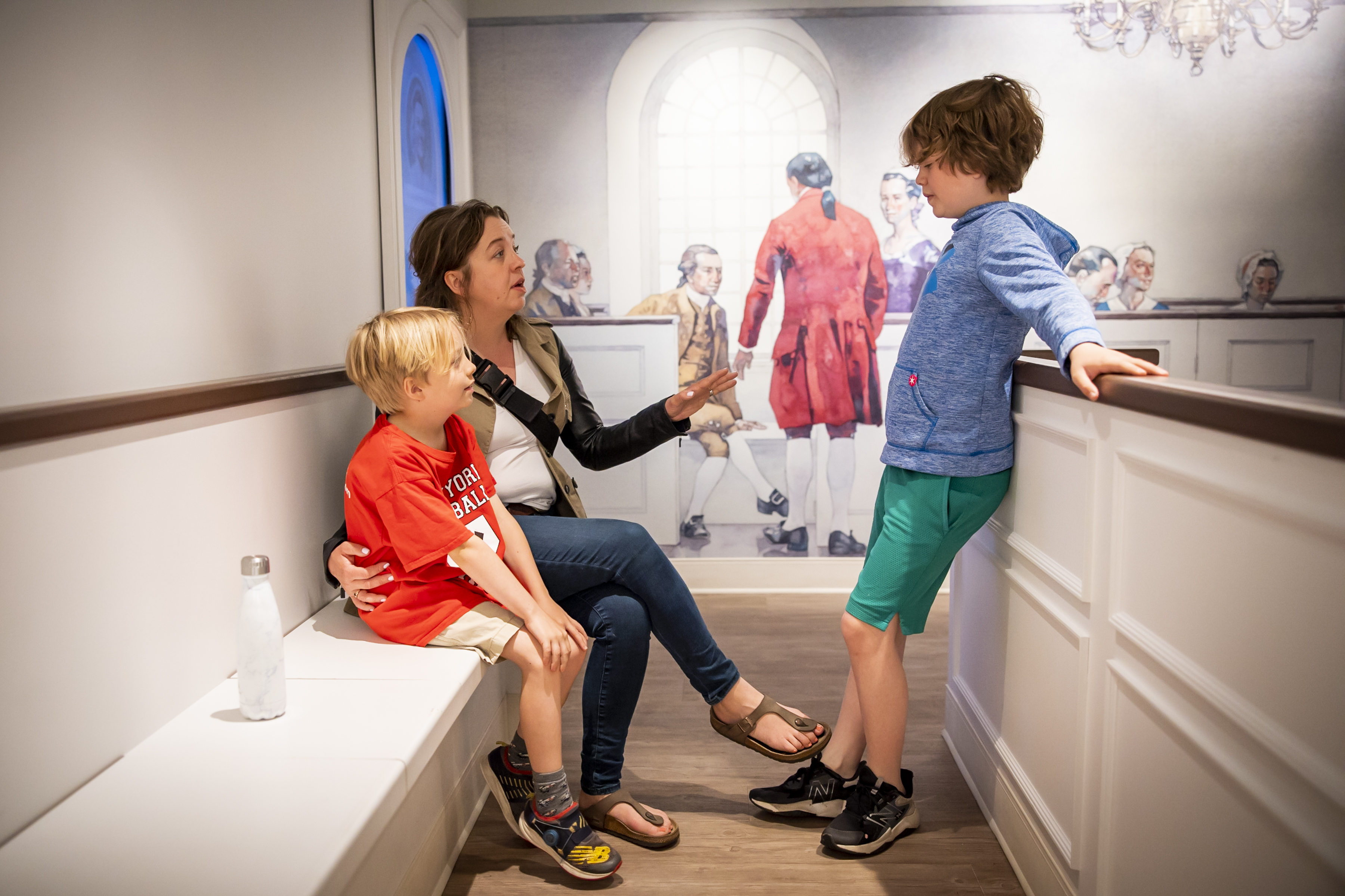 A mother and two children sit in the recreated 18th century church in Revolution Place.