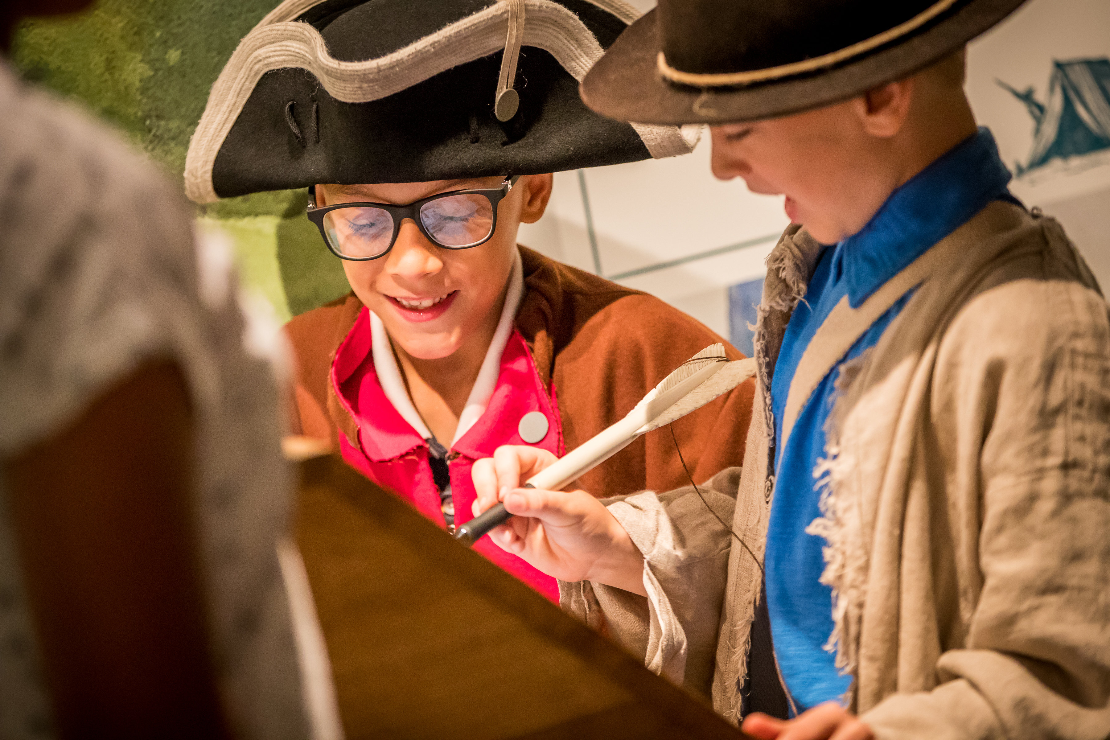 This image shows two adolescent males, in military costume, enjoying a digital feature in Revolution Place.