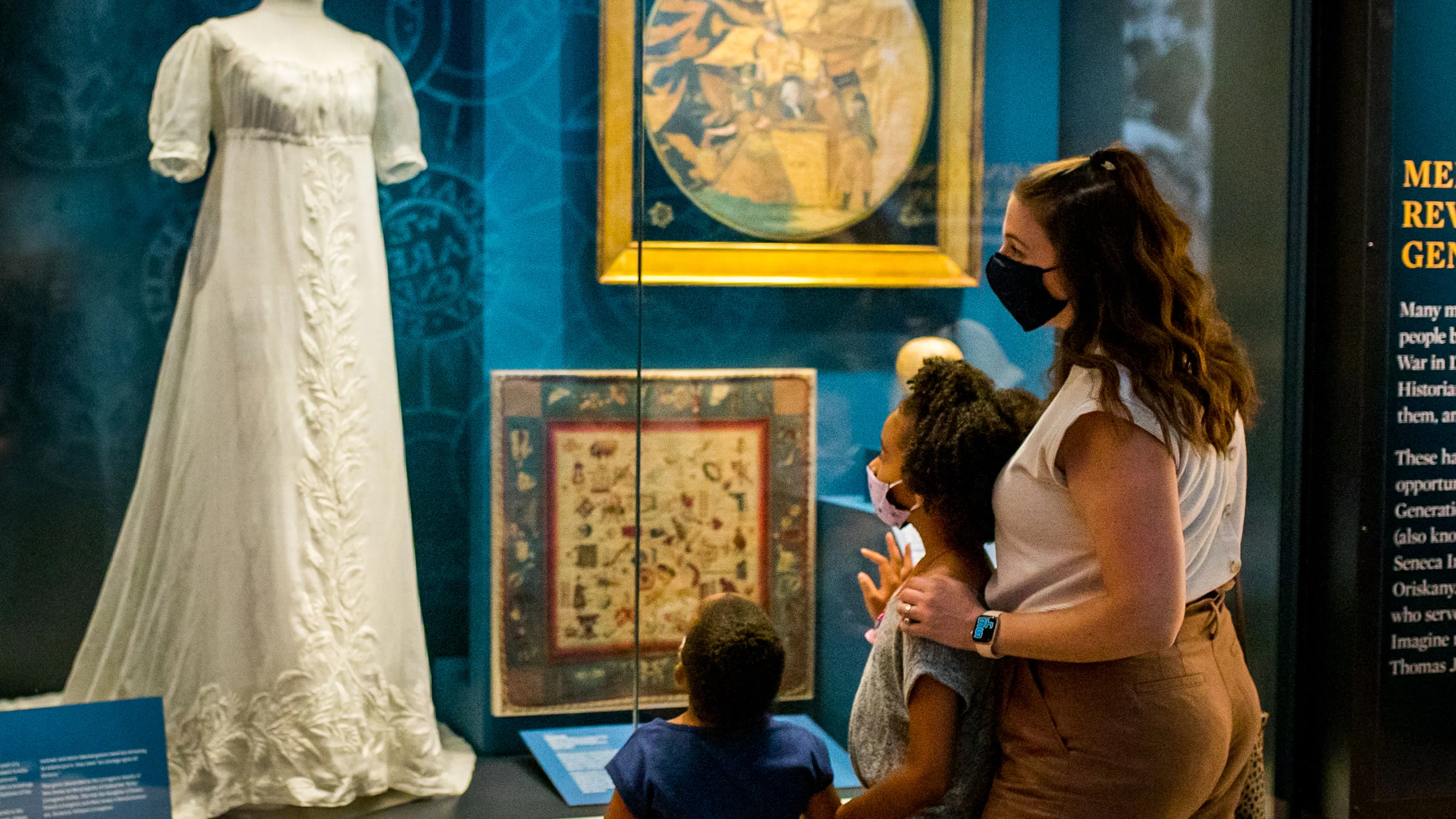 Family looking at a white dress in When Women Lost the Vote exhibit