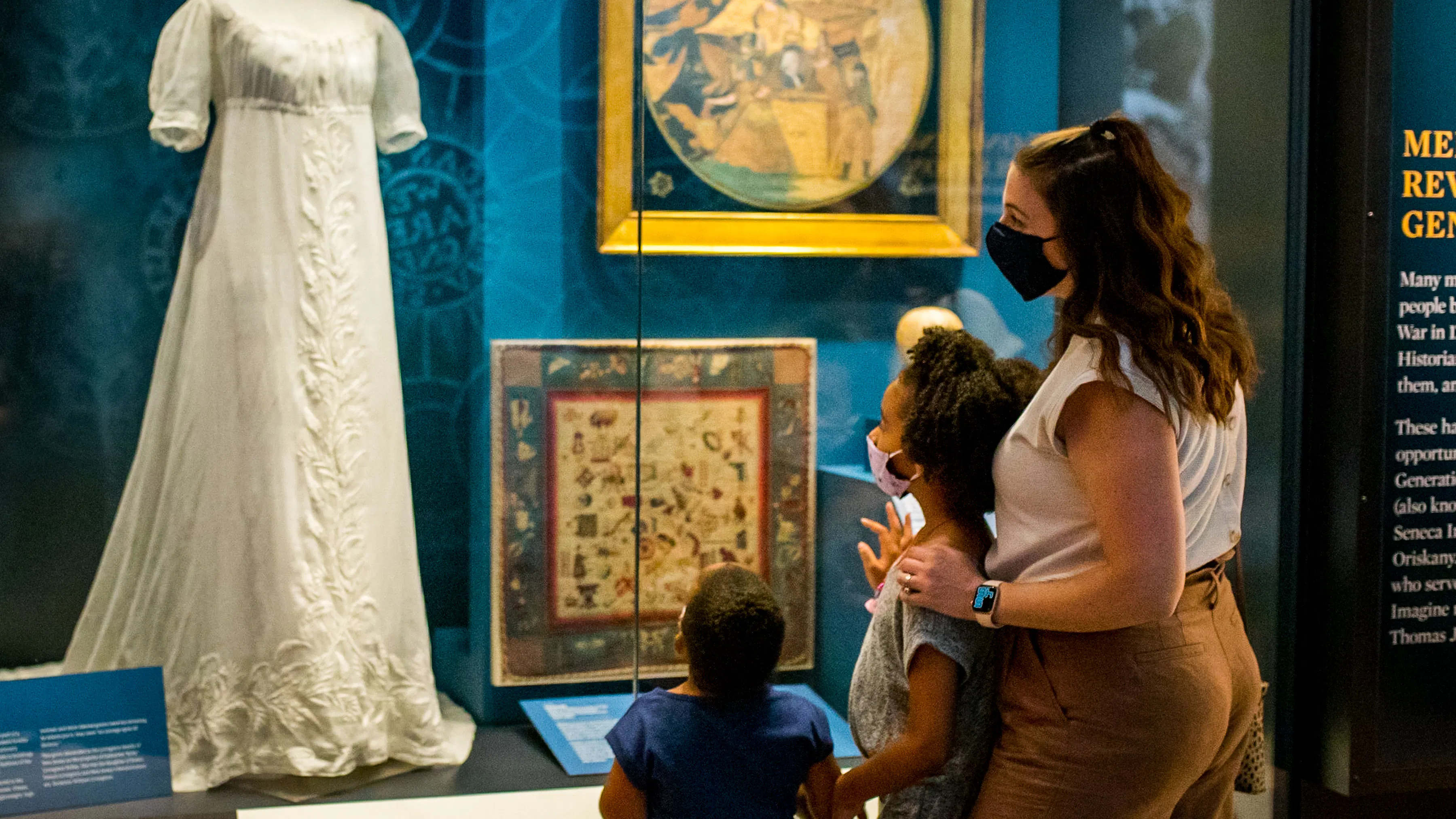 Family looking at a white dress in When Women Lost the Vote exhibit