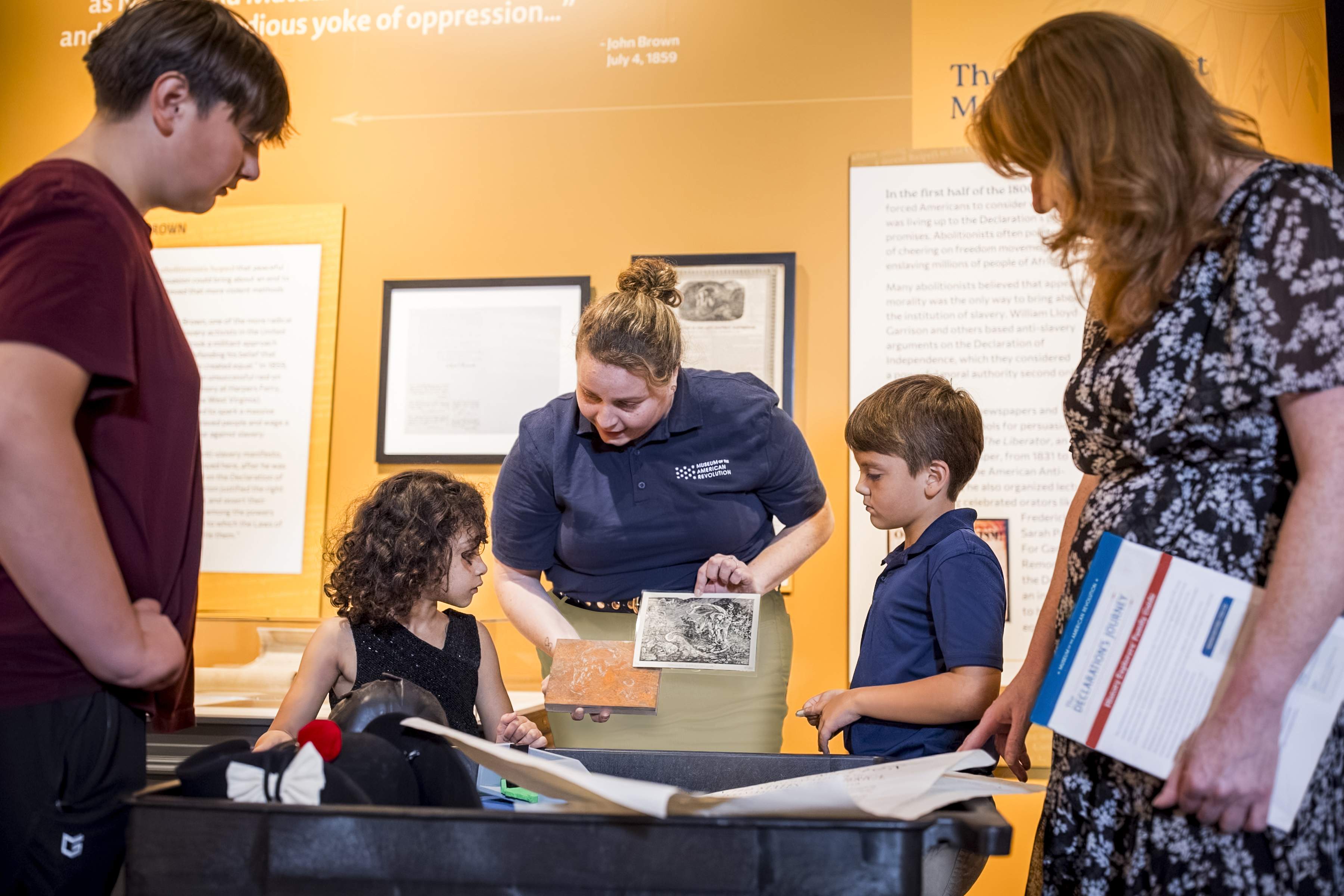 A Museum educator shows people objects on a discovery cart