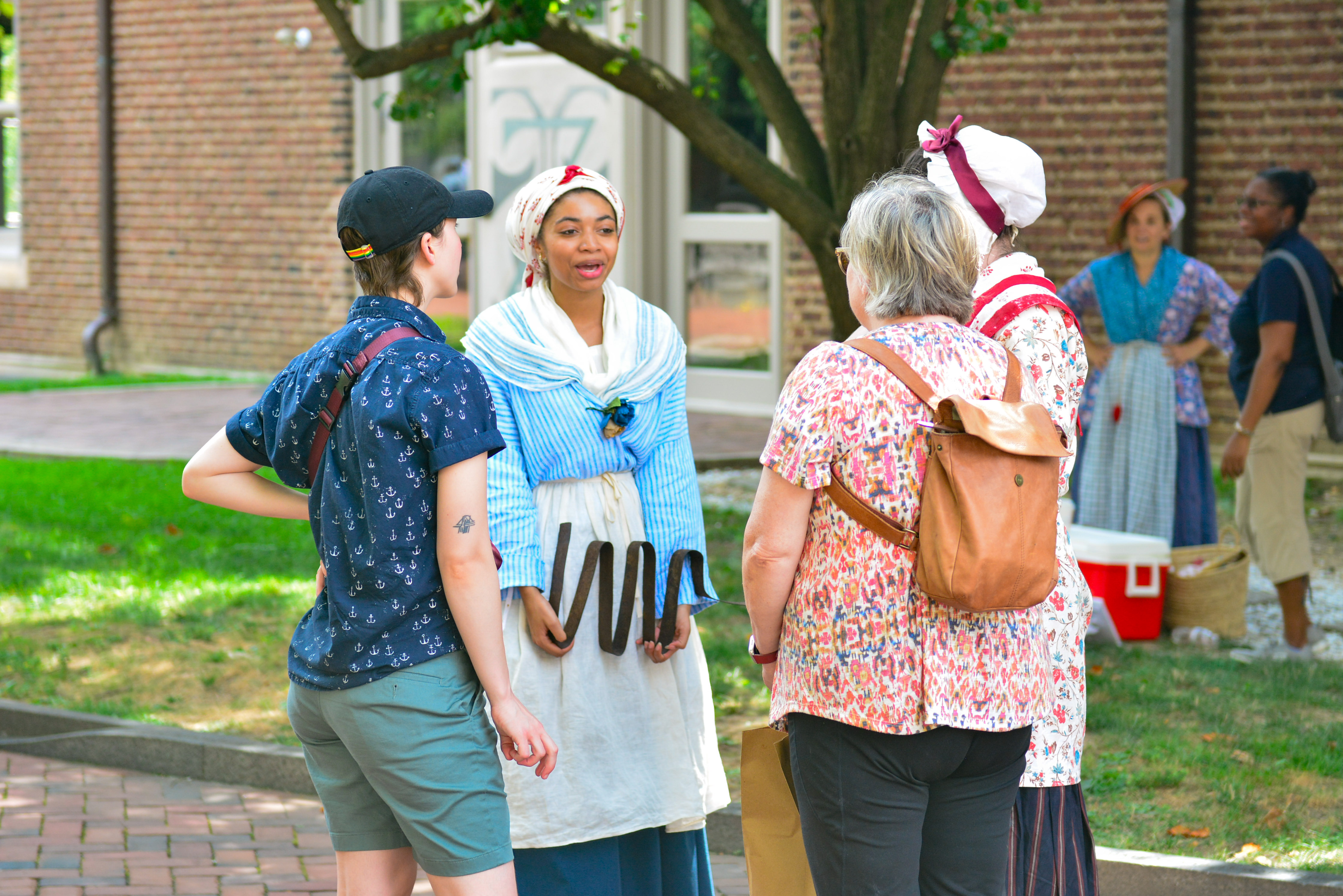 Two costumed interpreters stand with two people in modern day clothing