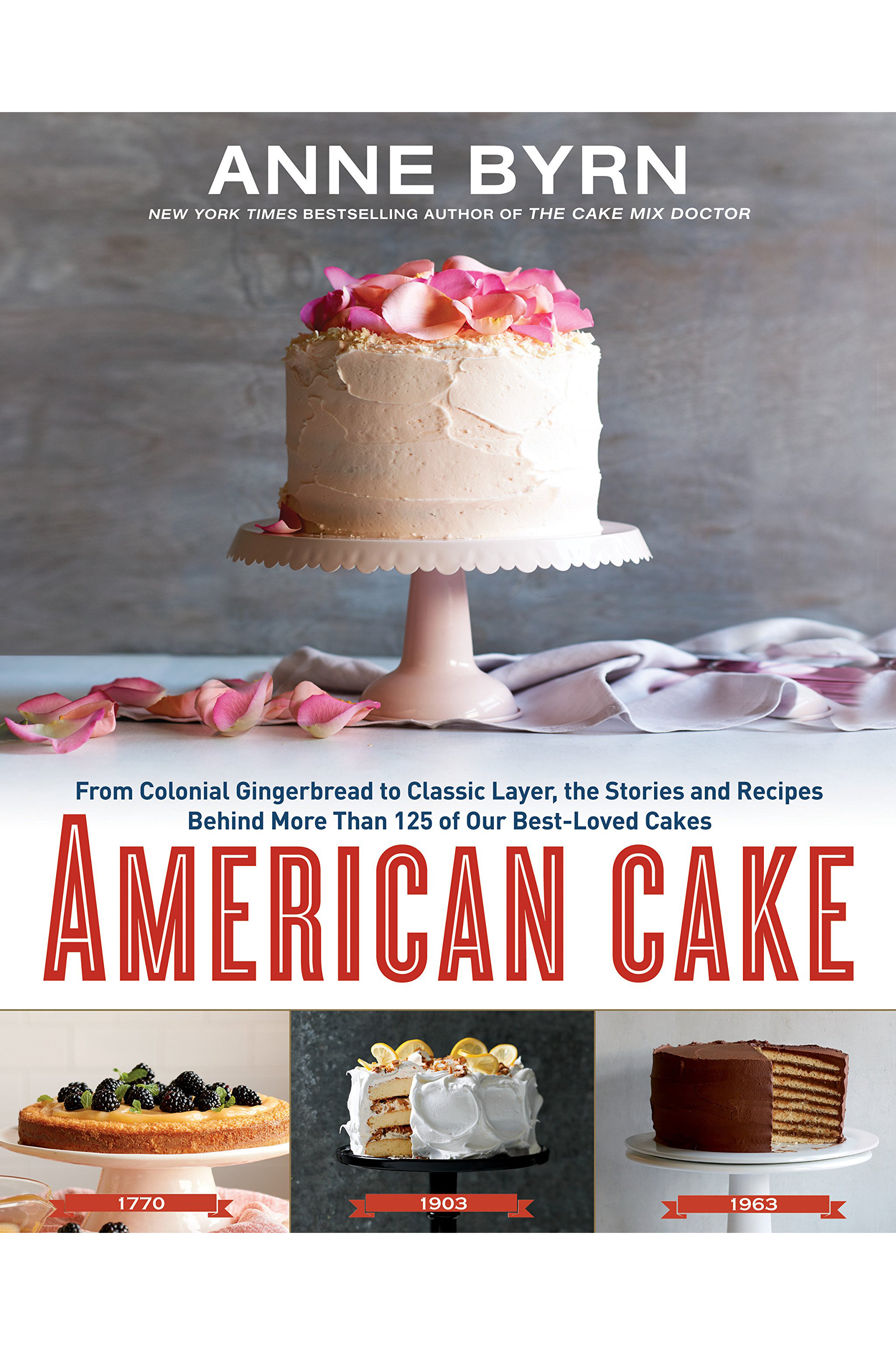This image depicts the book cover of American Cake by Anne Byrn. The book cover shows a white frosted cake with pink rose petals on top. The cake sits on a white cake stand with more petals surrounding the right side of the stand. Below this image is the title of the book. Below the title of the book are three smaller photographs of cakes dated 1770, 1903, and 1963.
