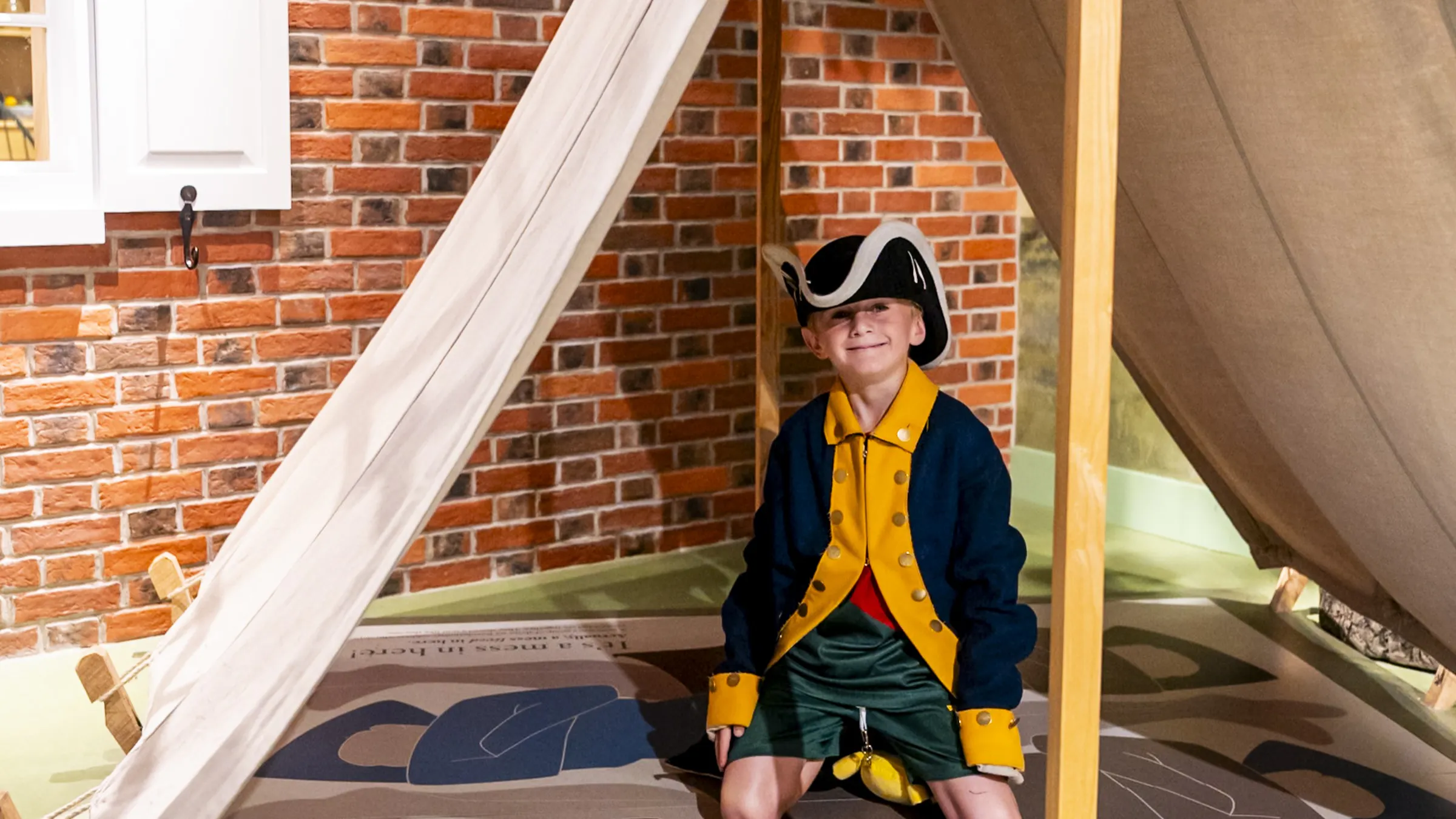 A child in a Revolutionary War costume kneels inside a tent