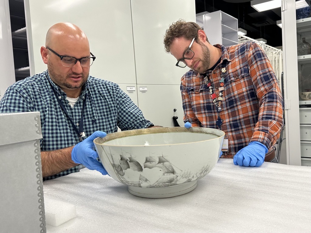 Two men look at a porcelain bowl