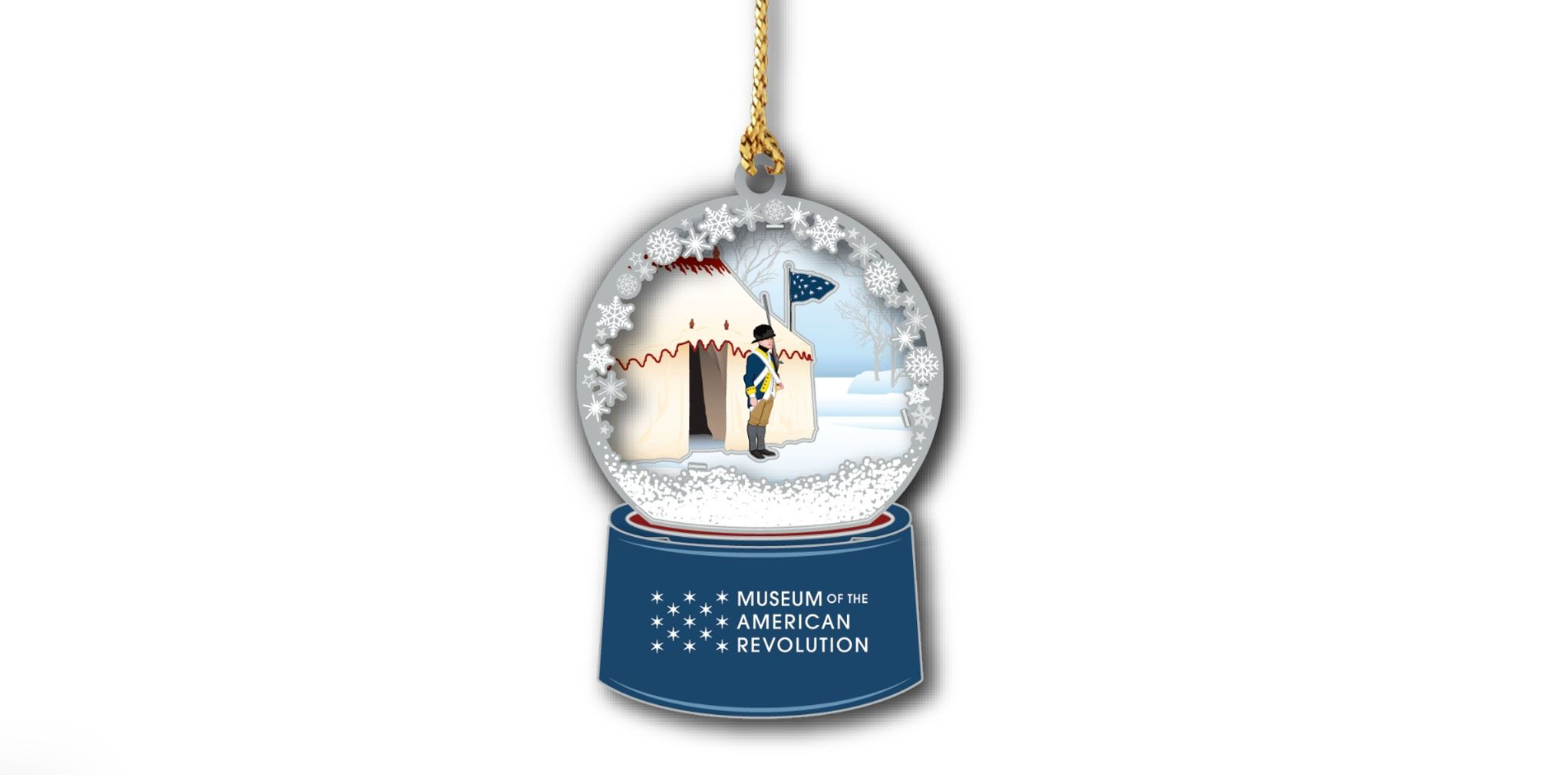This image shows a hanging tree ornament featuring a soldier standing guard outside General Washington’s tent in the snow