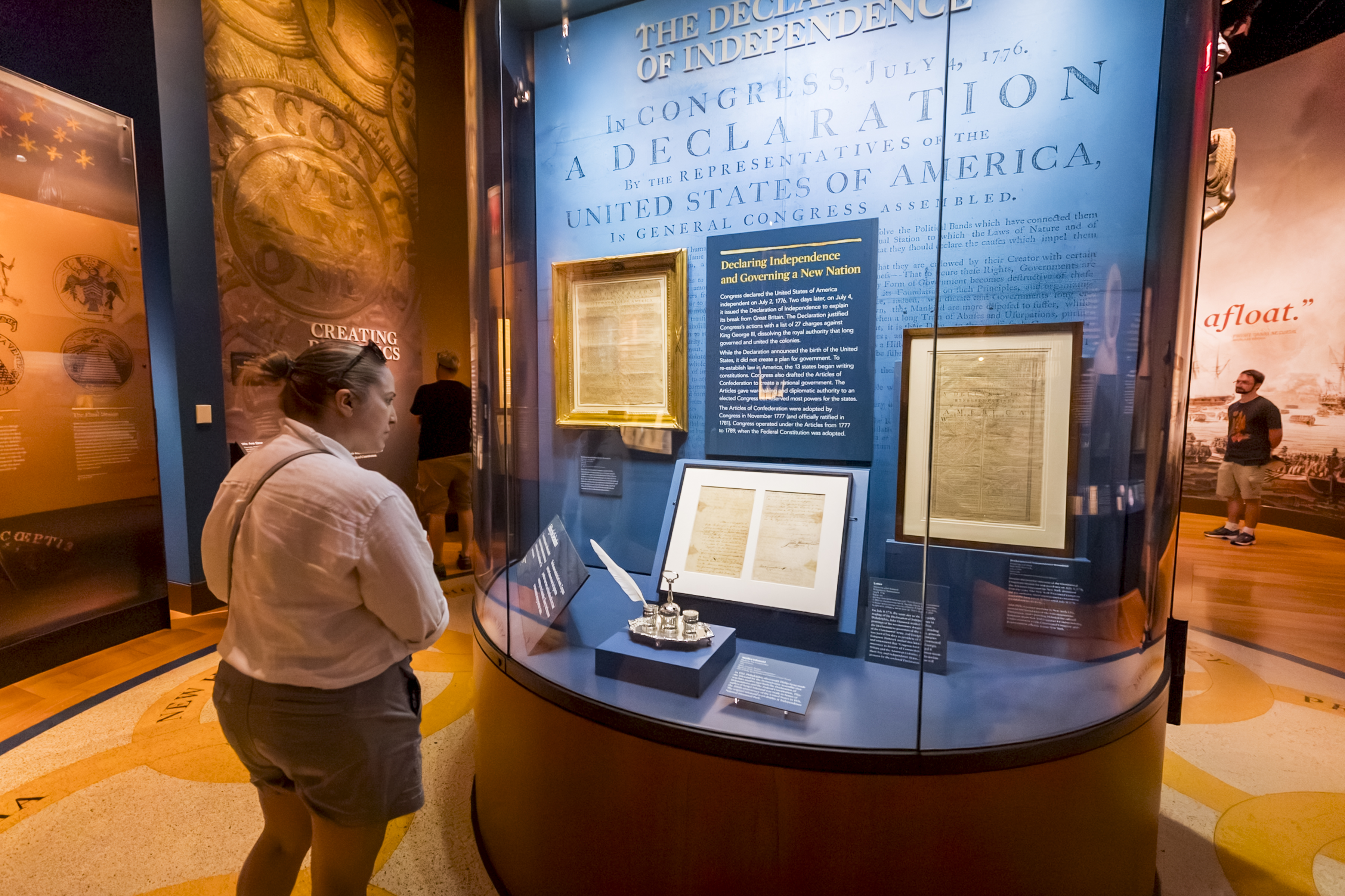 A visitor looks at framed Declaration of Independence broadsides in a display case