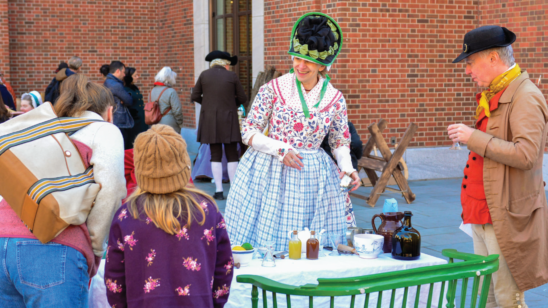 A photo of two costumed interpreters at a table with two Museum guests.