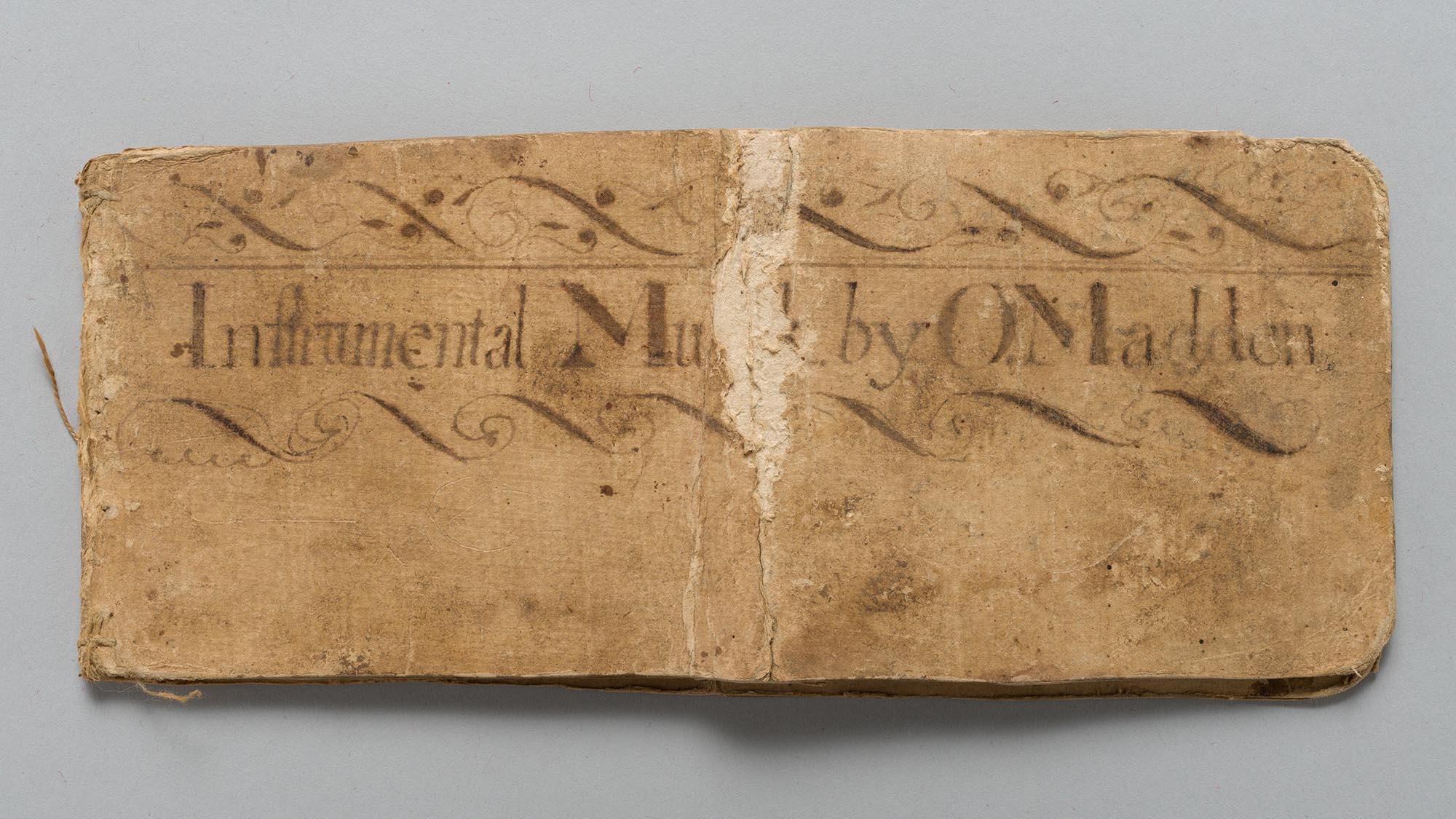 This image shows Owen Madden's tune book. It is rectangular and displayed against a plain, white background. The book is in good condition, but rather worn out in the middle running down the middle.