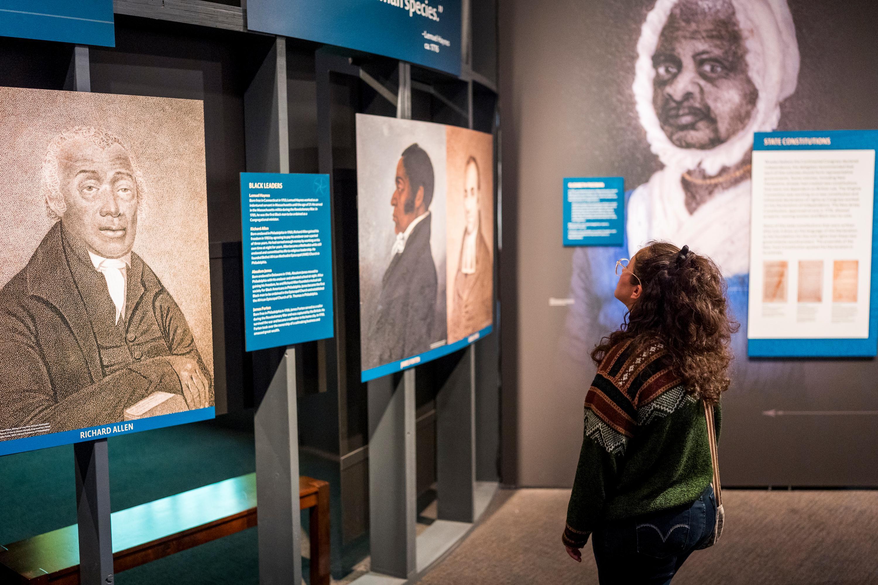 A visitor looks at mages of people of African descent in "The Declaration's Journey"