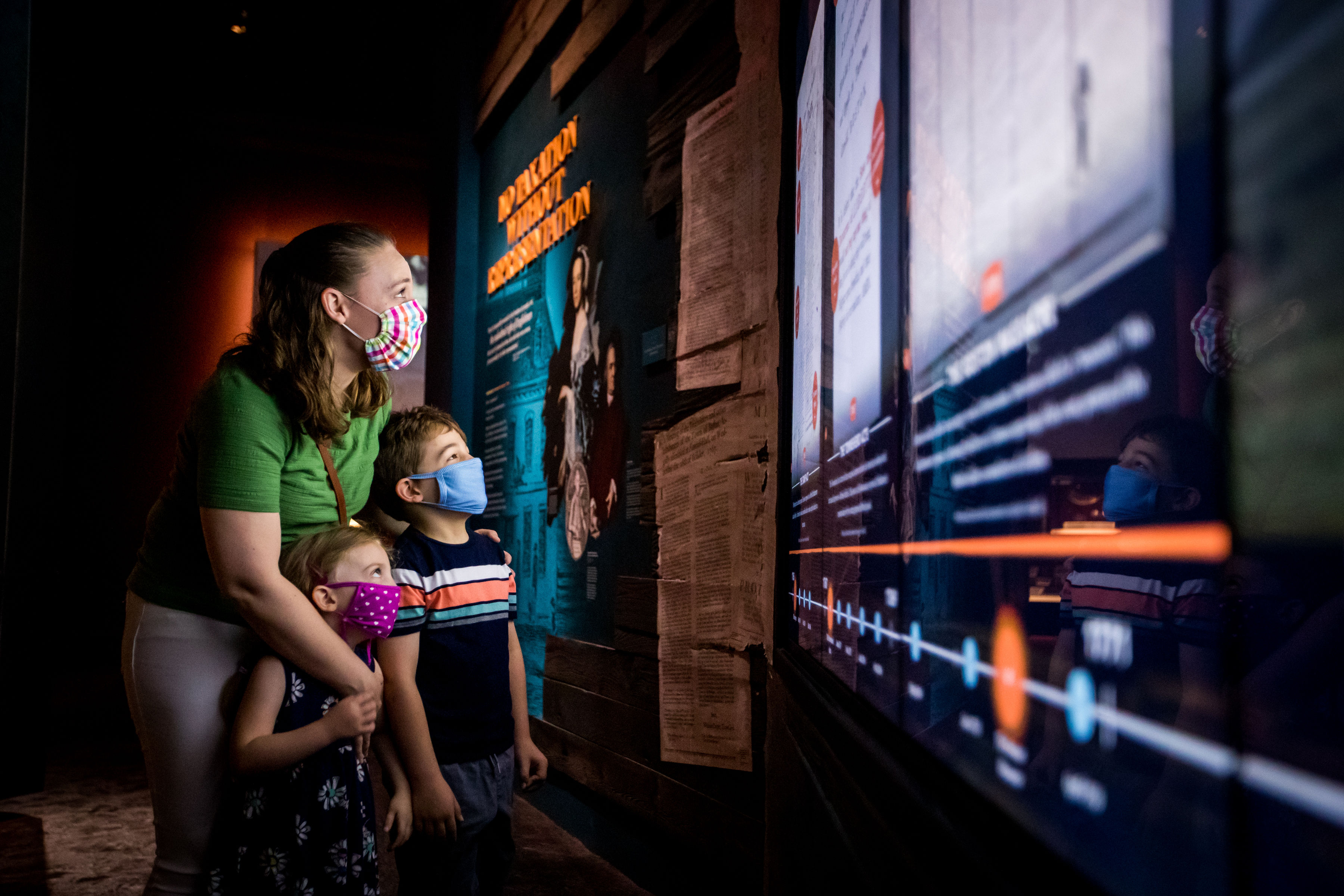 A mother and her two children, wearing masks, explore the galleries.