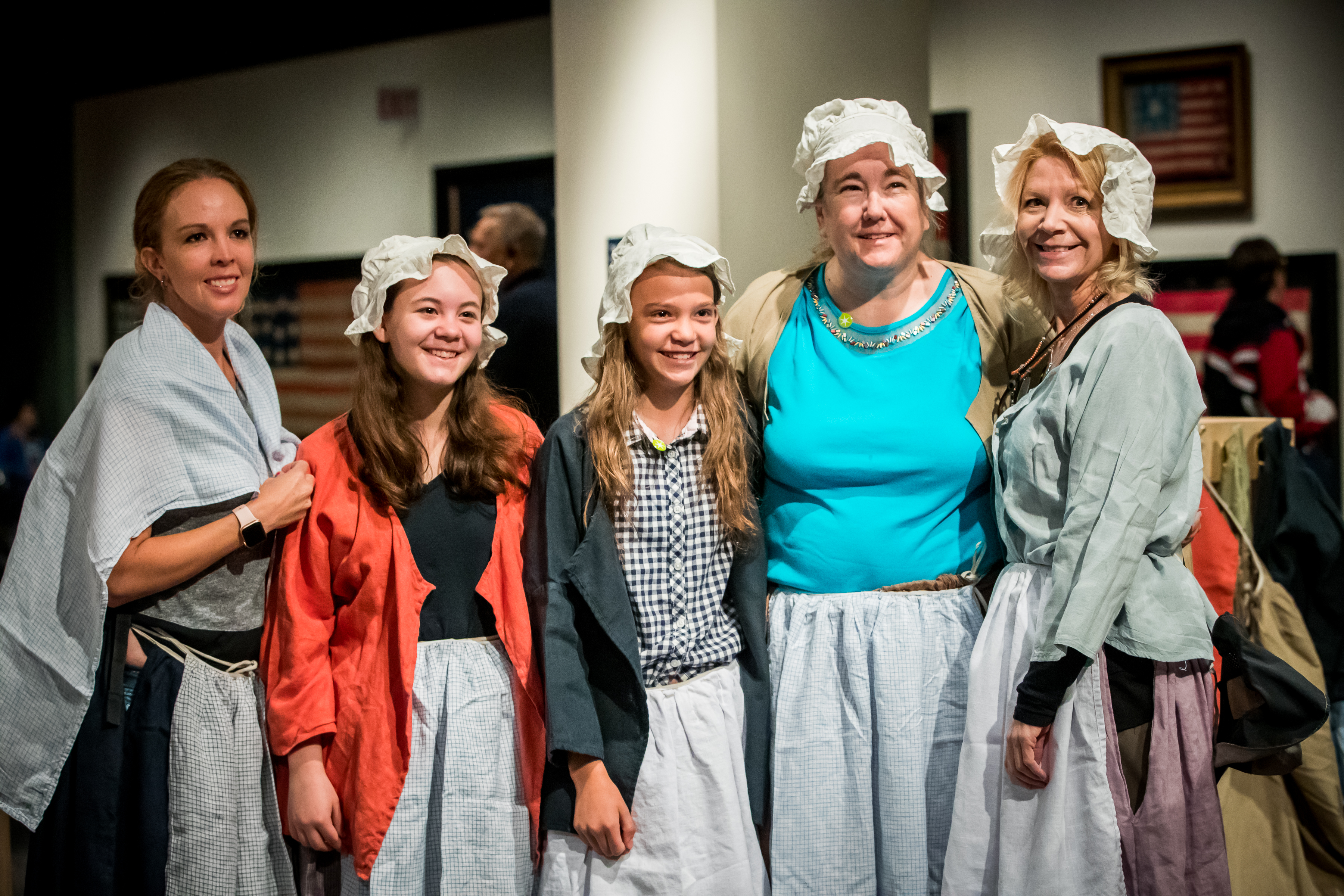 Five female guests, wearing Revolution-era costumes, pose for a picture.