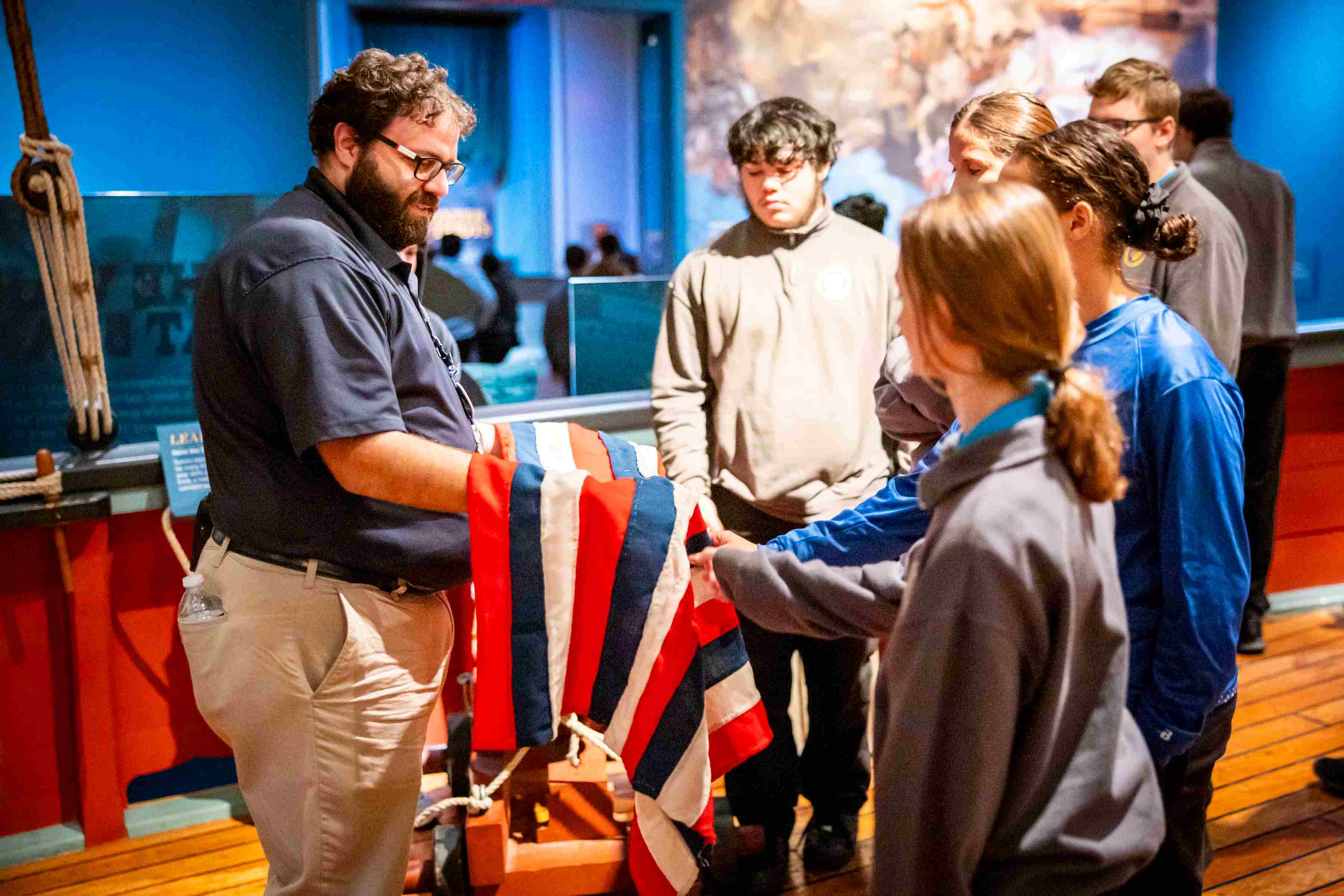 An educator holds a replica flag for a group of visitors