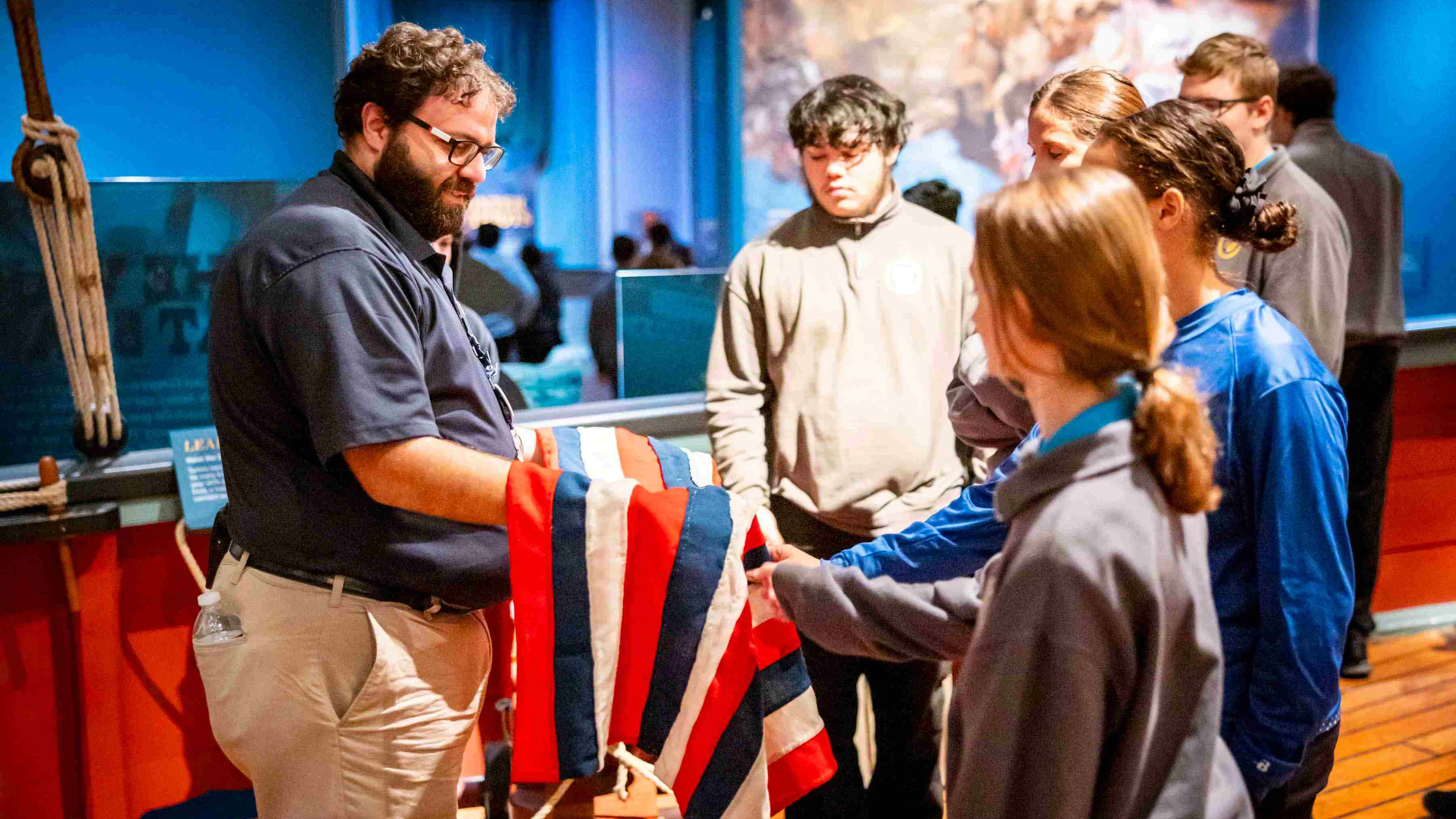 An educator holds a replica flag for a group of visitors