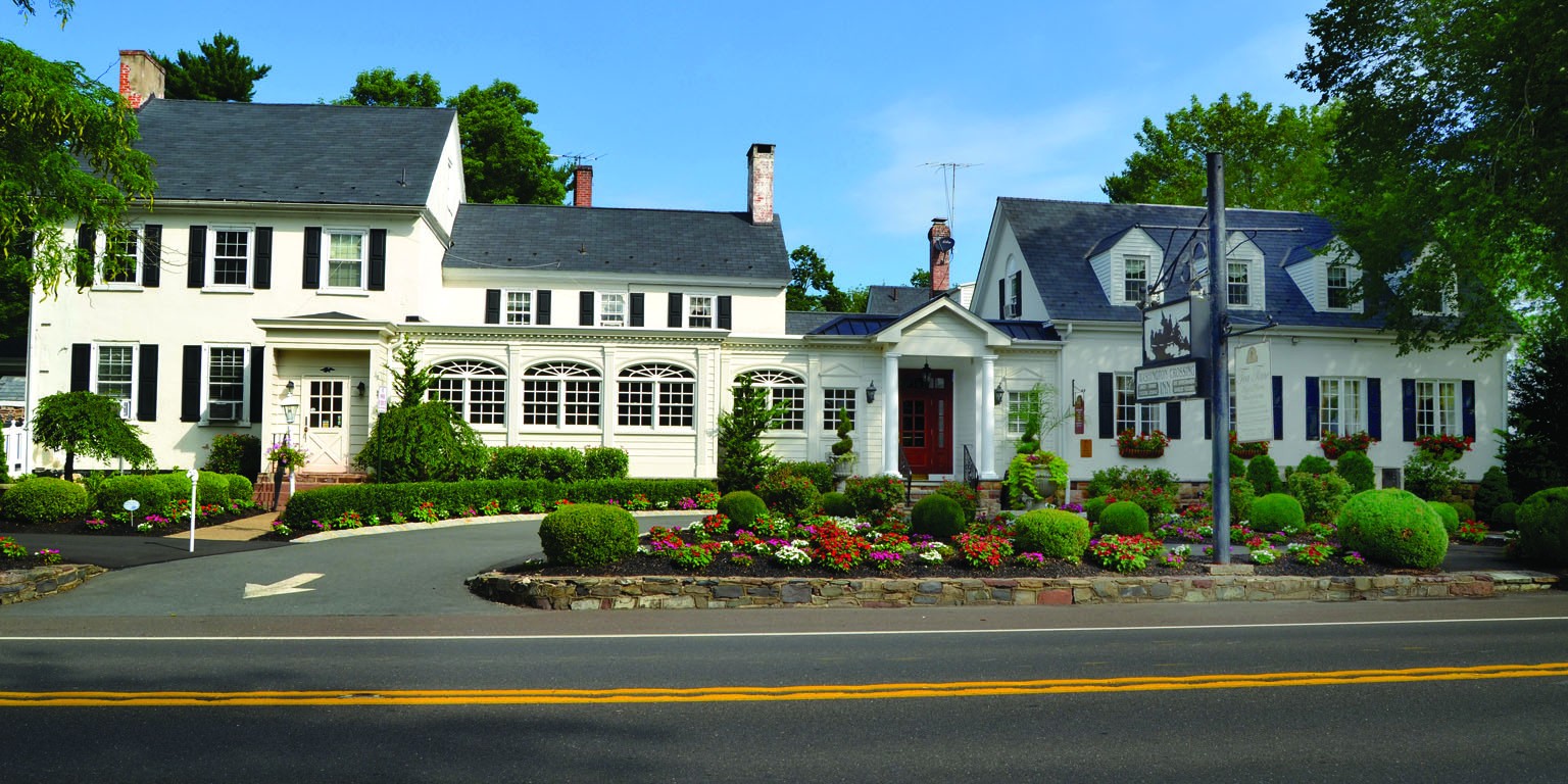 This image shows the long white 18th century inn with black shutters and details.