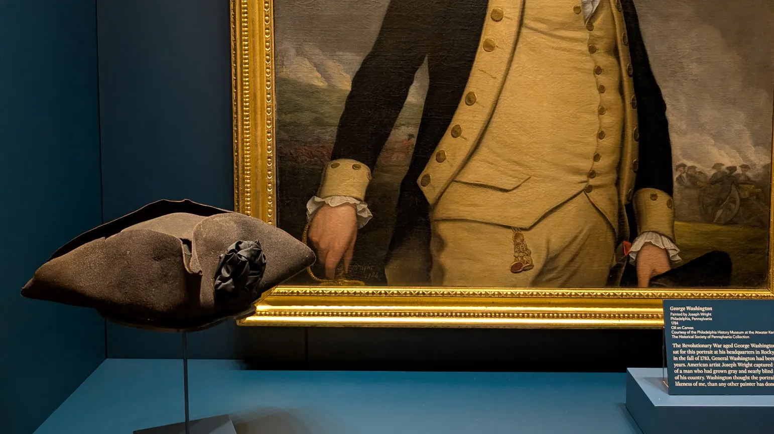 A hat and a portrait in a display case