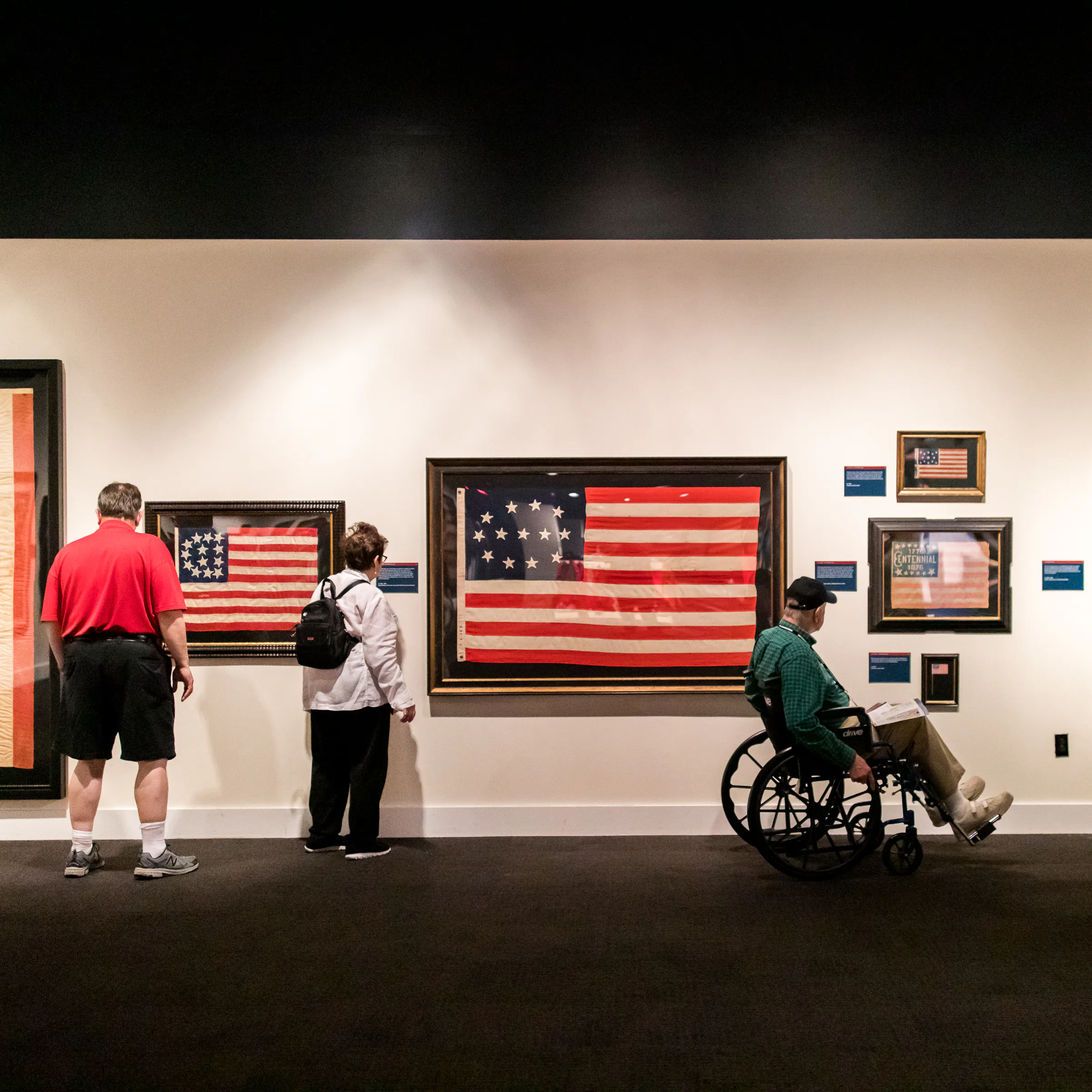 Museum patrons looking at various Revolutionary-era American flags in the "Banners of Liberty" Museum exhibit