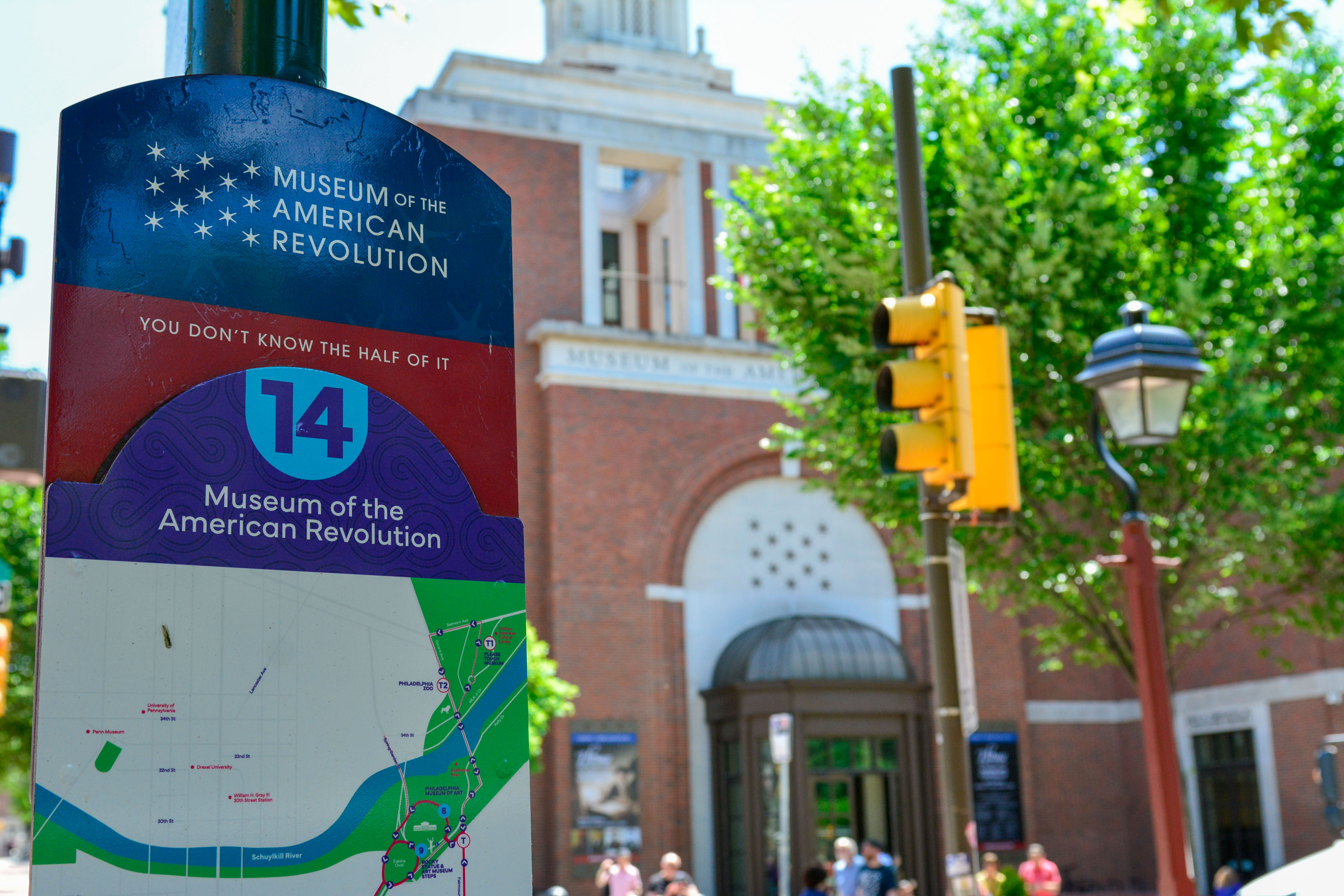 Purple PHLASH bus sign with the stop number 14, the museum of the american revolution logo in white, and a map of the bus route.