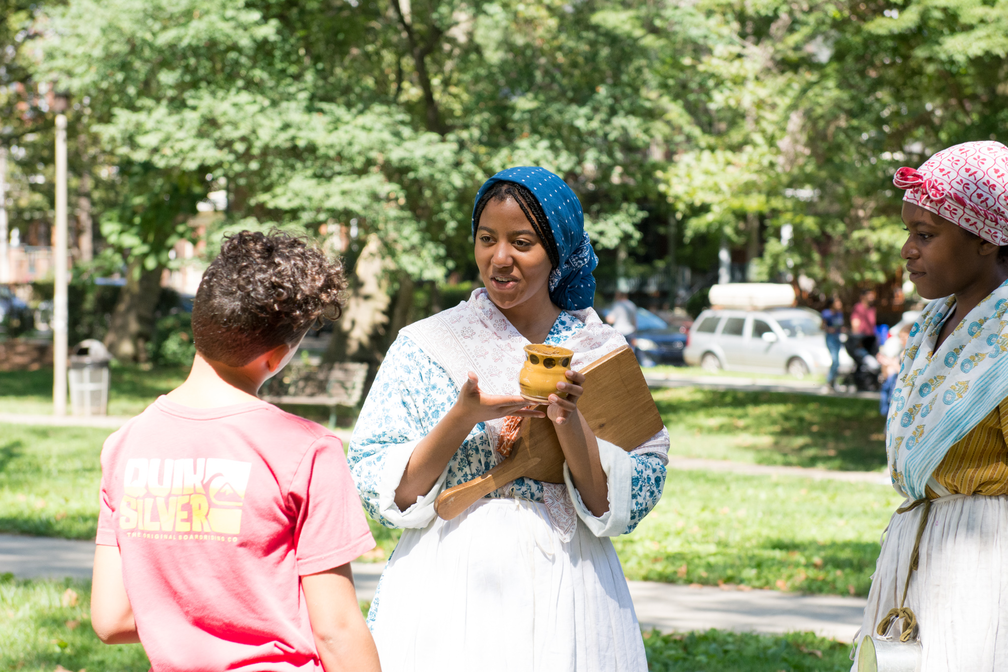 A costumed interpreter shows guests an artifact