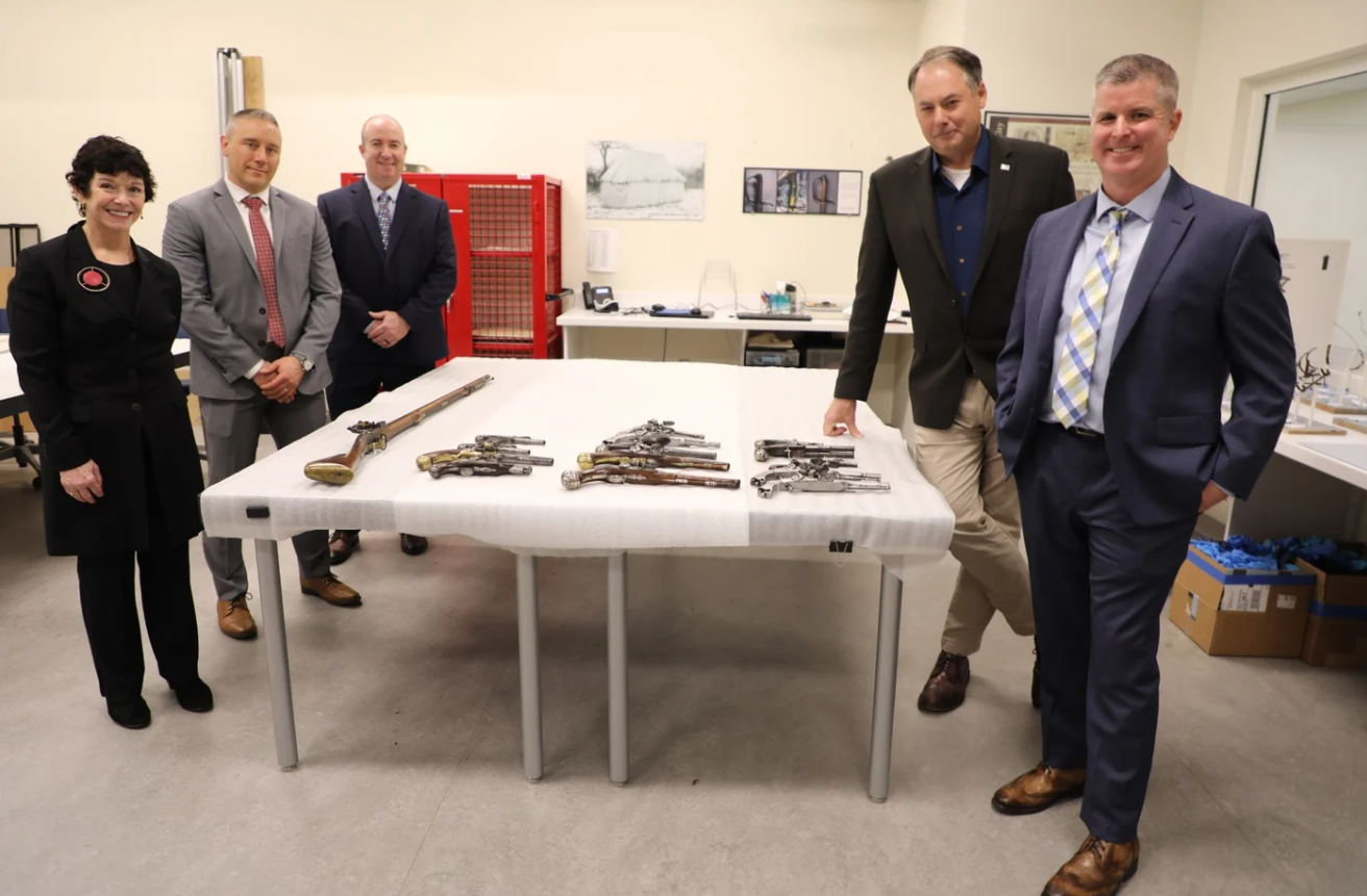 Assistant U.S. Attorney K.T. Newton of the U.S. Attorney's Office for the Eastern District of Pennsylvania, FBI Philadelphia Special Agent Jake Archer, Detective Andy Rathfon of the Upper Merion Township Police Department in Pennsylvania, Museum of the American Revolution President and CEO Scott Stephenson, and Upper Merion Township Police Detective Brendan Dougherty pose alongside Revolutionary War-era firearms they collectively helped recover