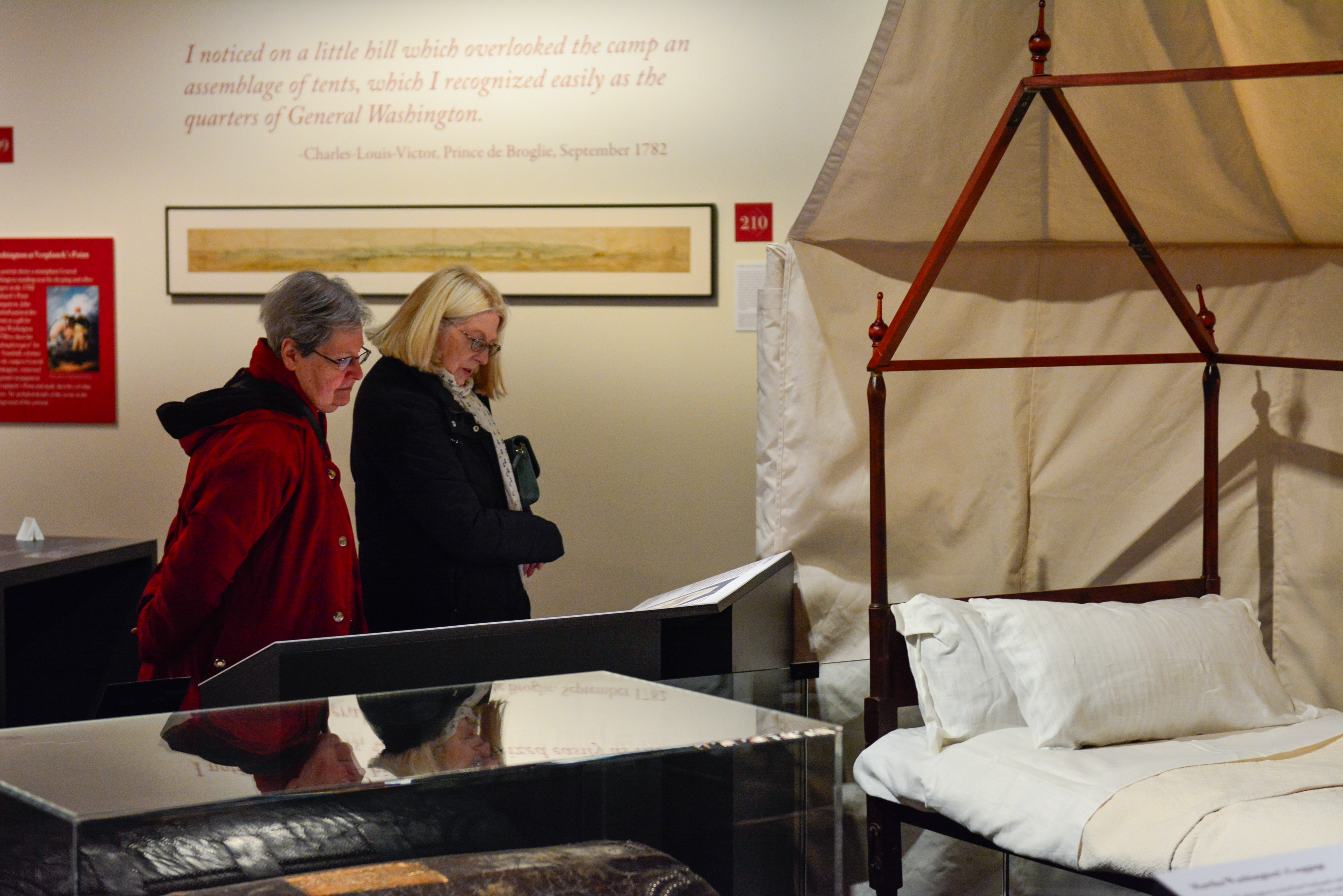 Two members view the wooden structure of Washington's camp bed on display in the Witness to Revolution exhibit.