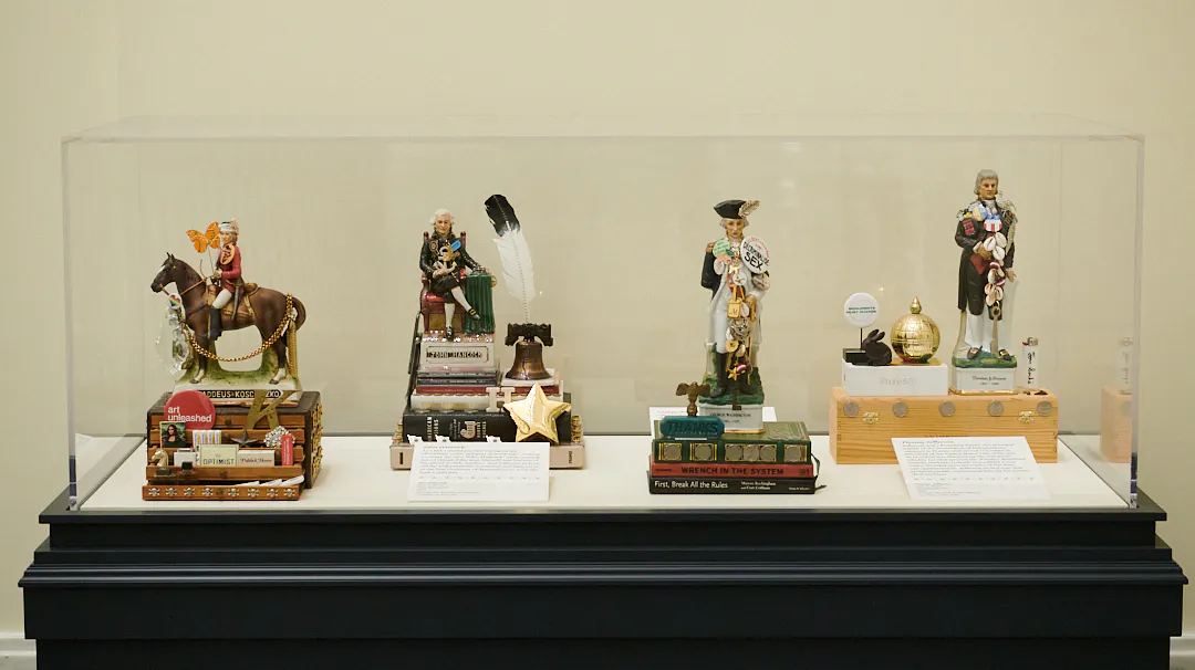 A case displays four of John Wind's Whiskey Rebellion pieces including those decpicting Thaddeus Kosciuszko, John Hancock, George Washington, and Thomas Jefferson.