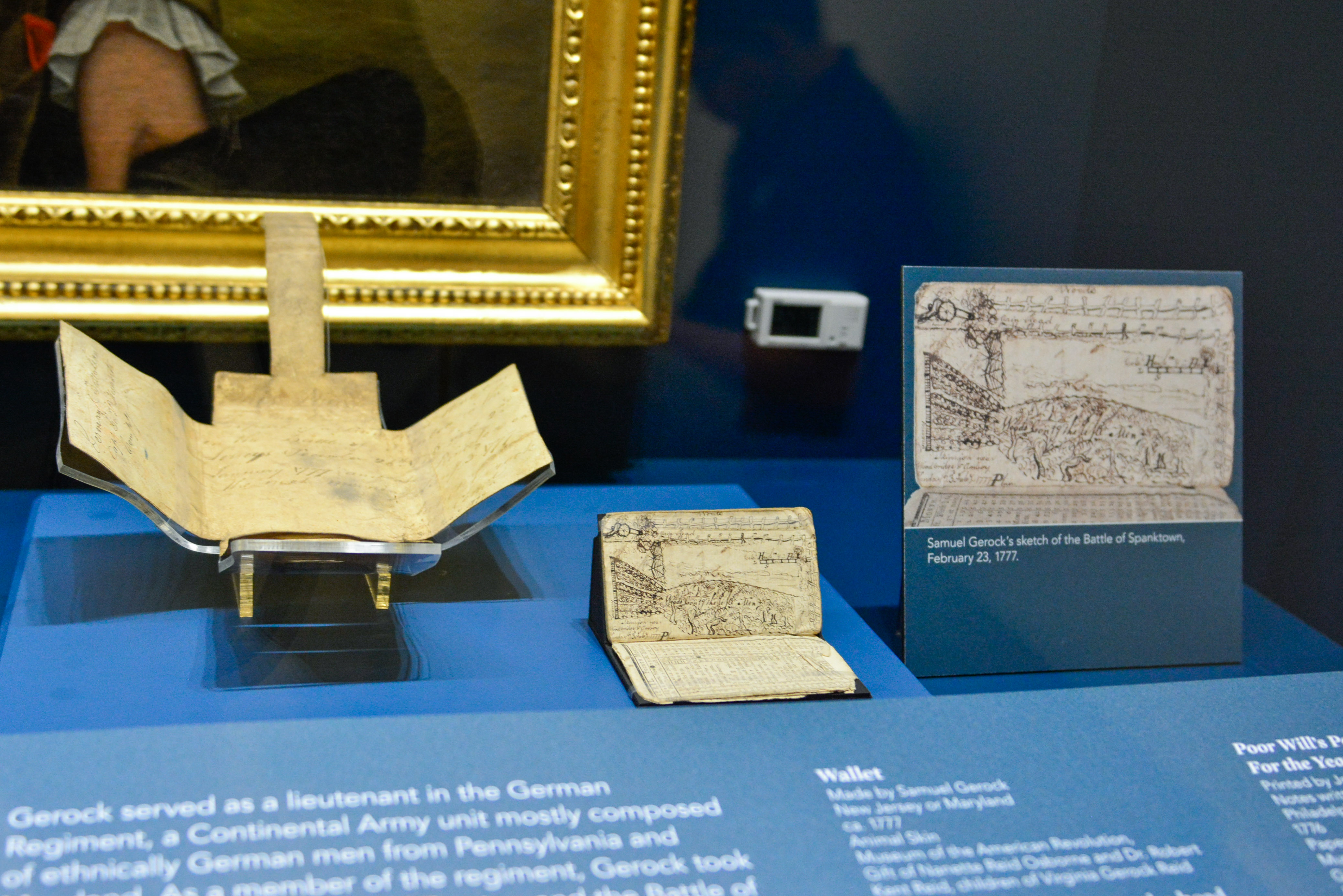 This image shows an open wallet and an open pocket almanac that belonged to Samuel Gerock on display at the Museum.