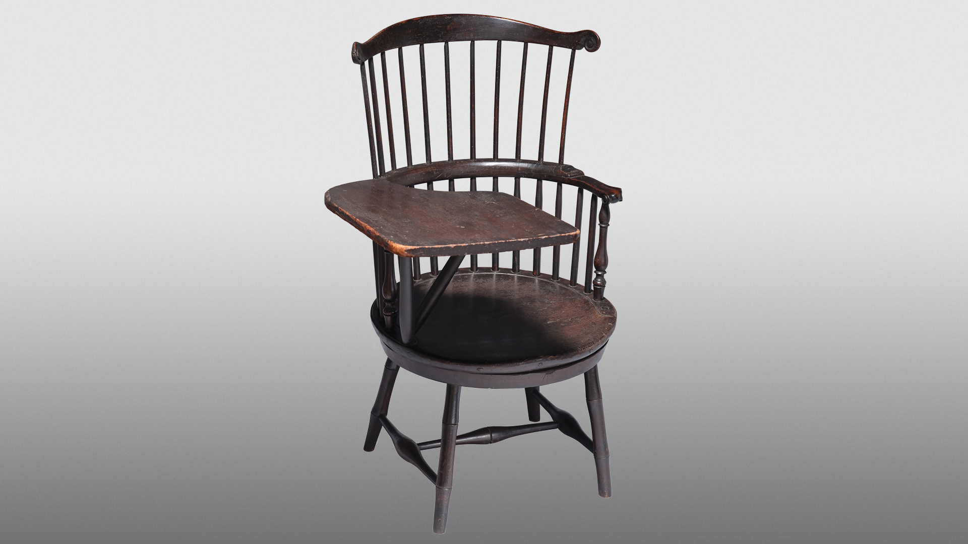 A brown chair wooden chair with a small writing desk attached