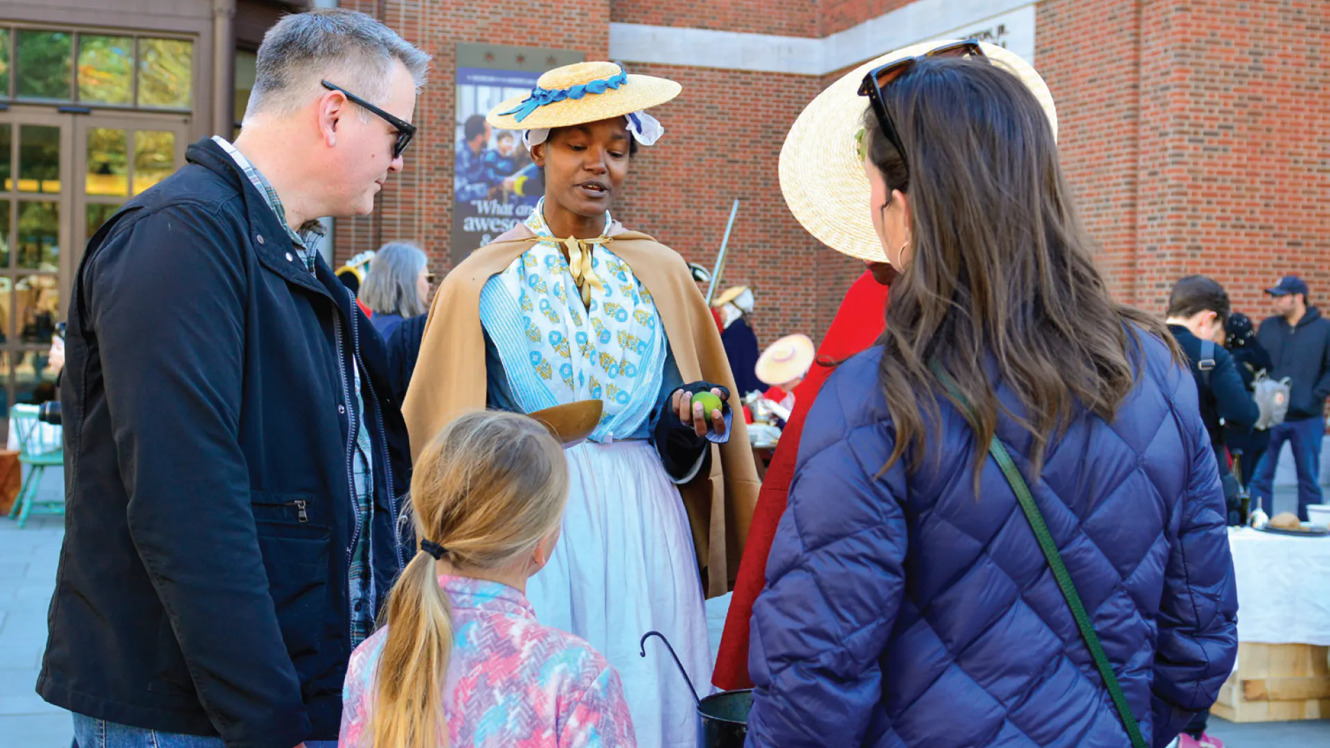 A costumed interpreter and two people standing in front of the Museum