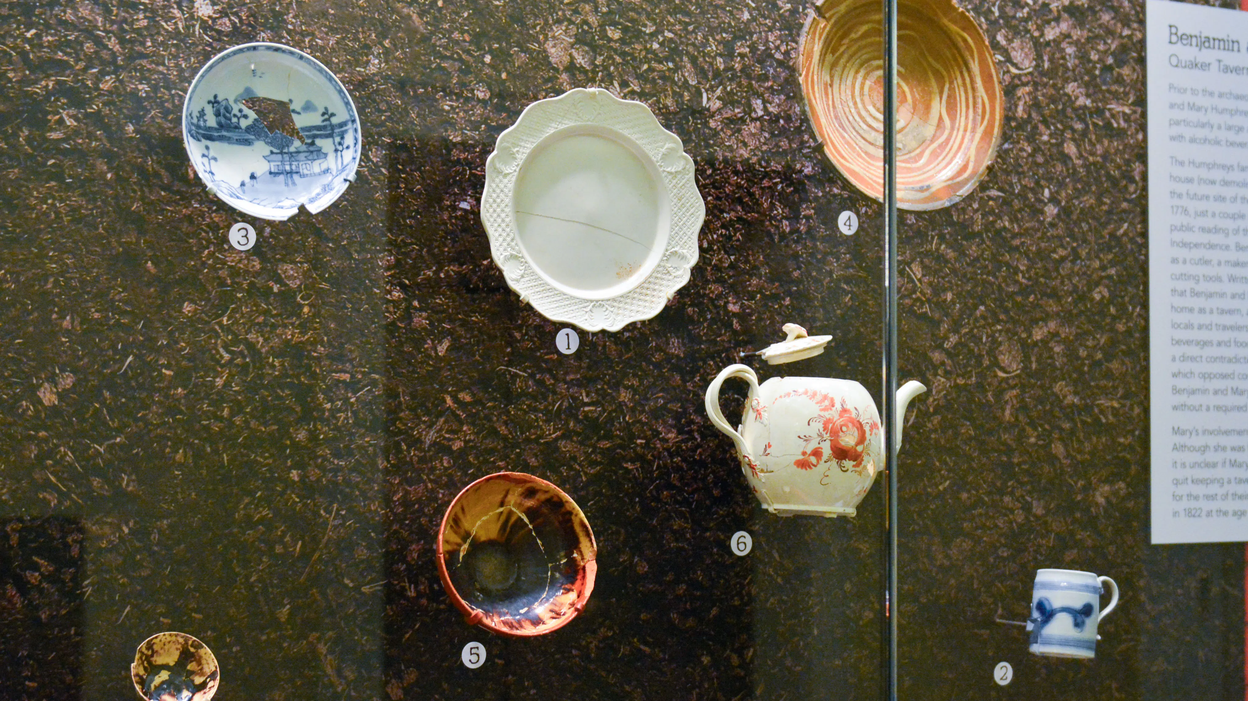 This image shows a collection of seven reconstructed ceramic pieces that were found in a privy pit at the site of the Museum.