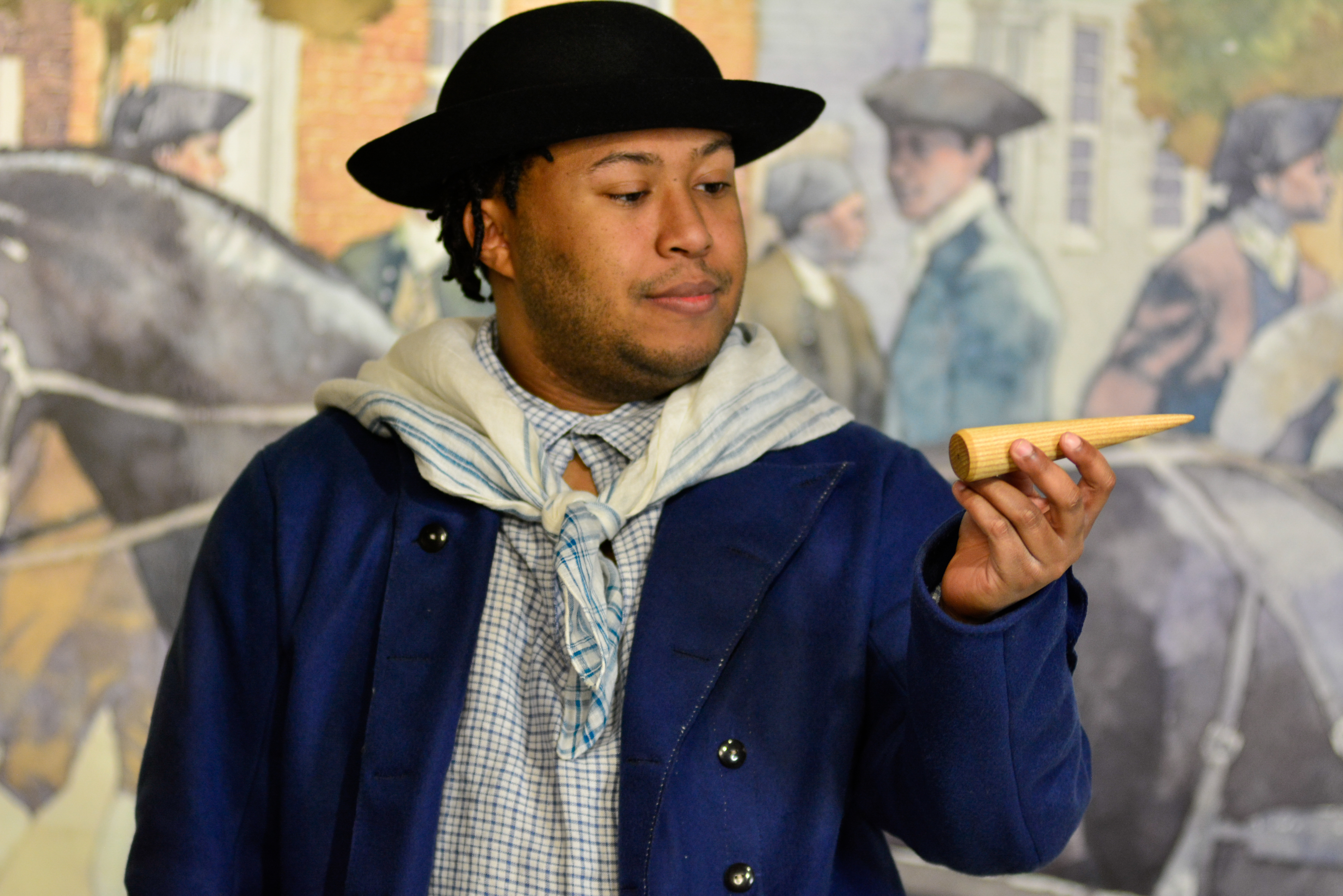 Actor Nathan Alford-Tate depicts a sailor in a blue coat holding a sailmaking fid in our Meet James Forten first-person theatrical performance.