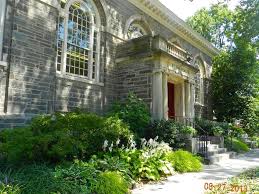 Gray stone facade of the Chestnut Hill Library with cream white detaills and columns in front of the entrance.