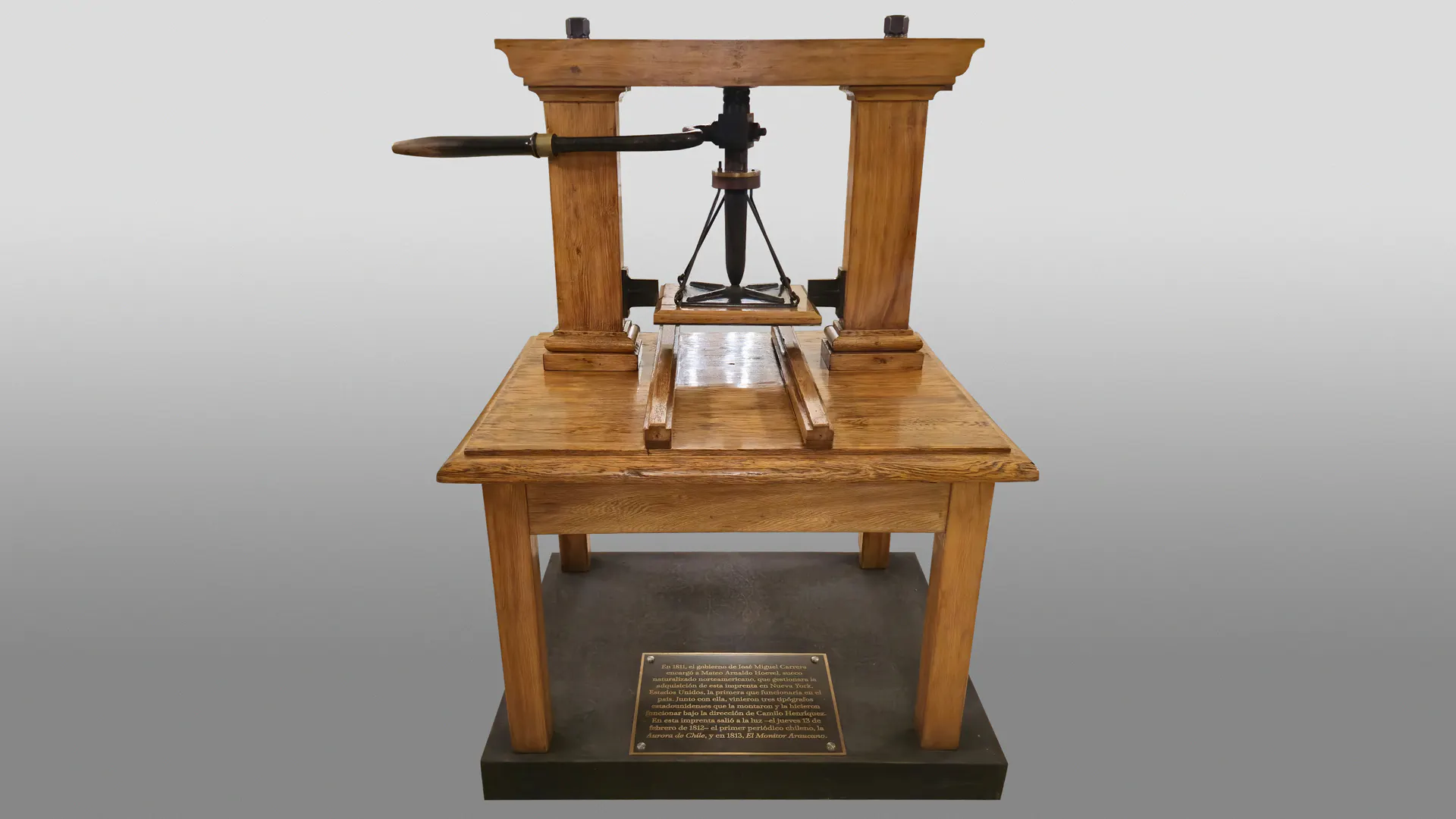 A wooden printing press with a plaque underneath on a neutral background