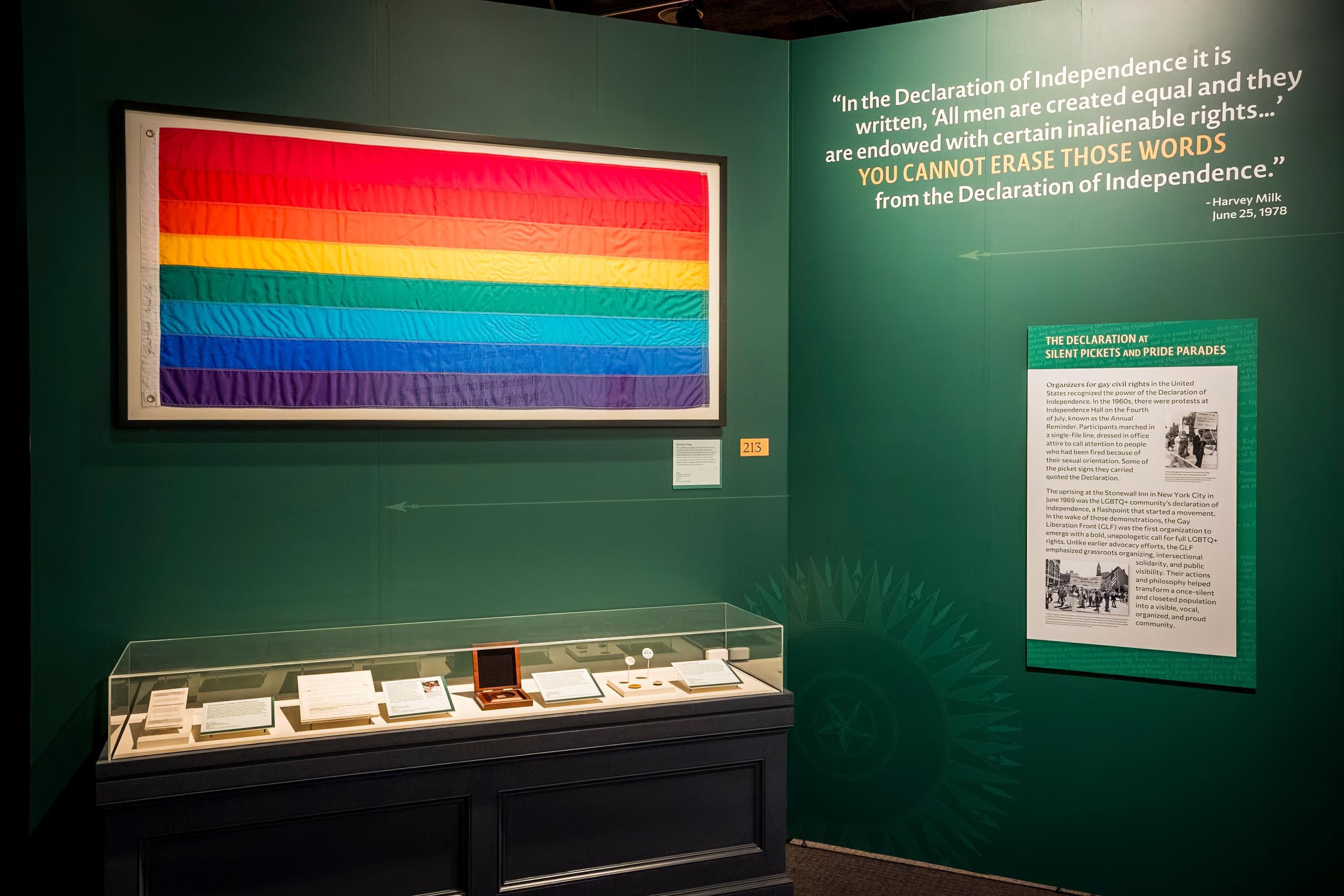 A Pride flag and artifacts displayed in The Declaration's Journey