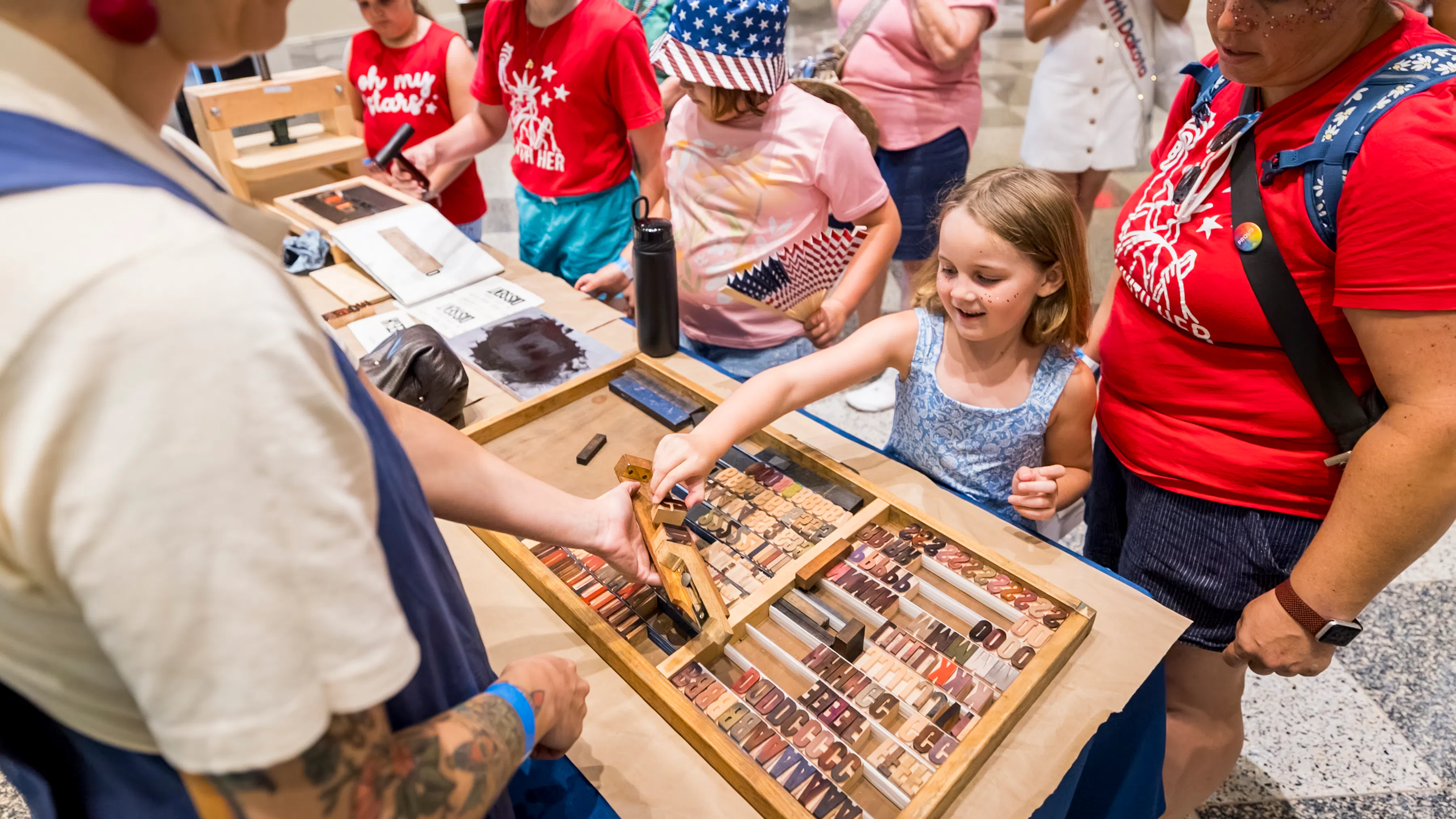 Girl choosing printing press molds while two women look on