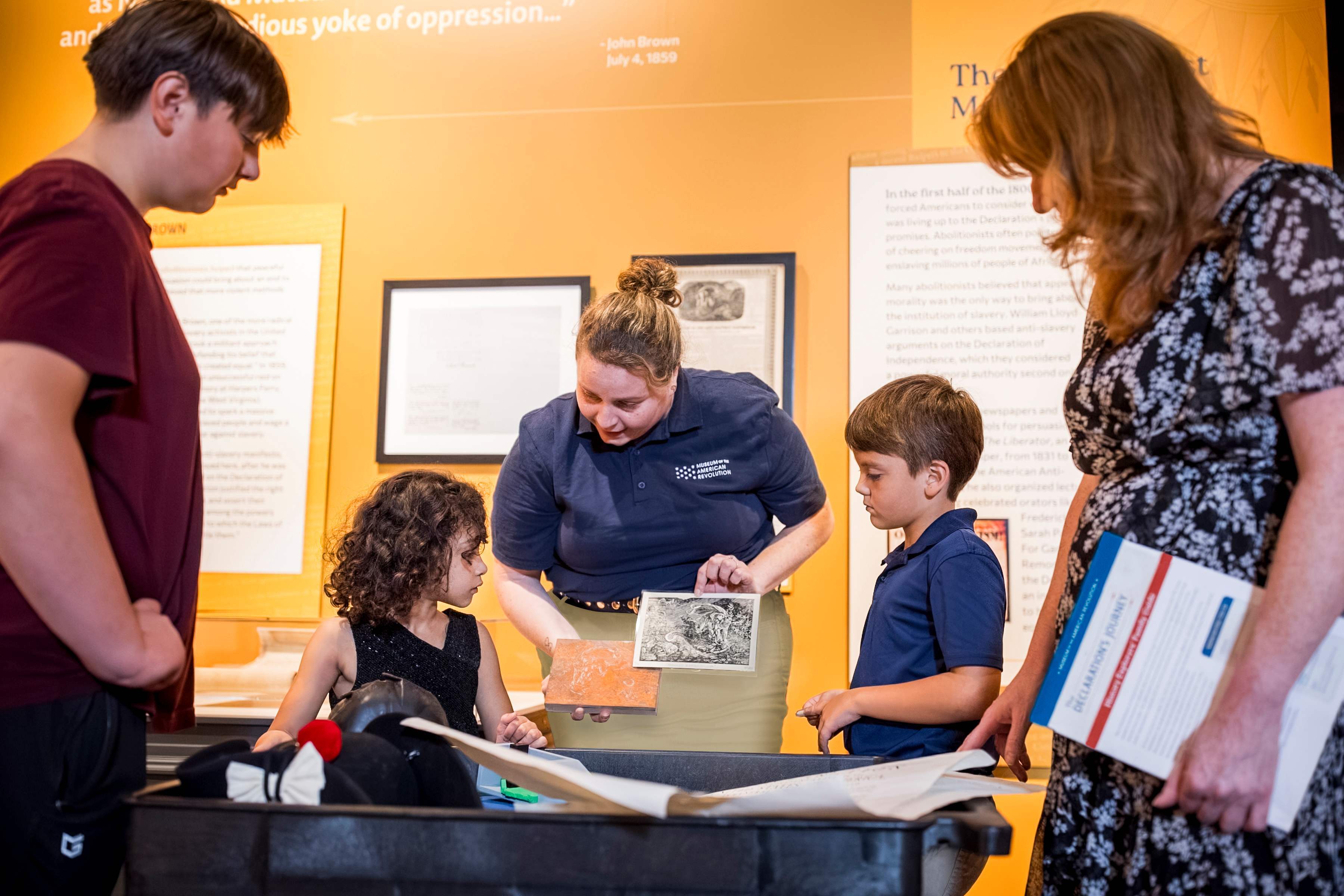 A Museum educator shows people objects on a discovery cart
