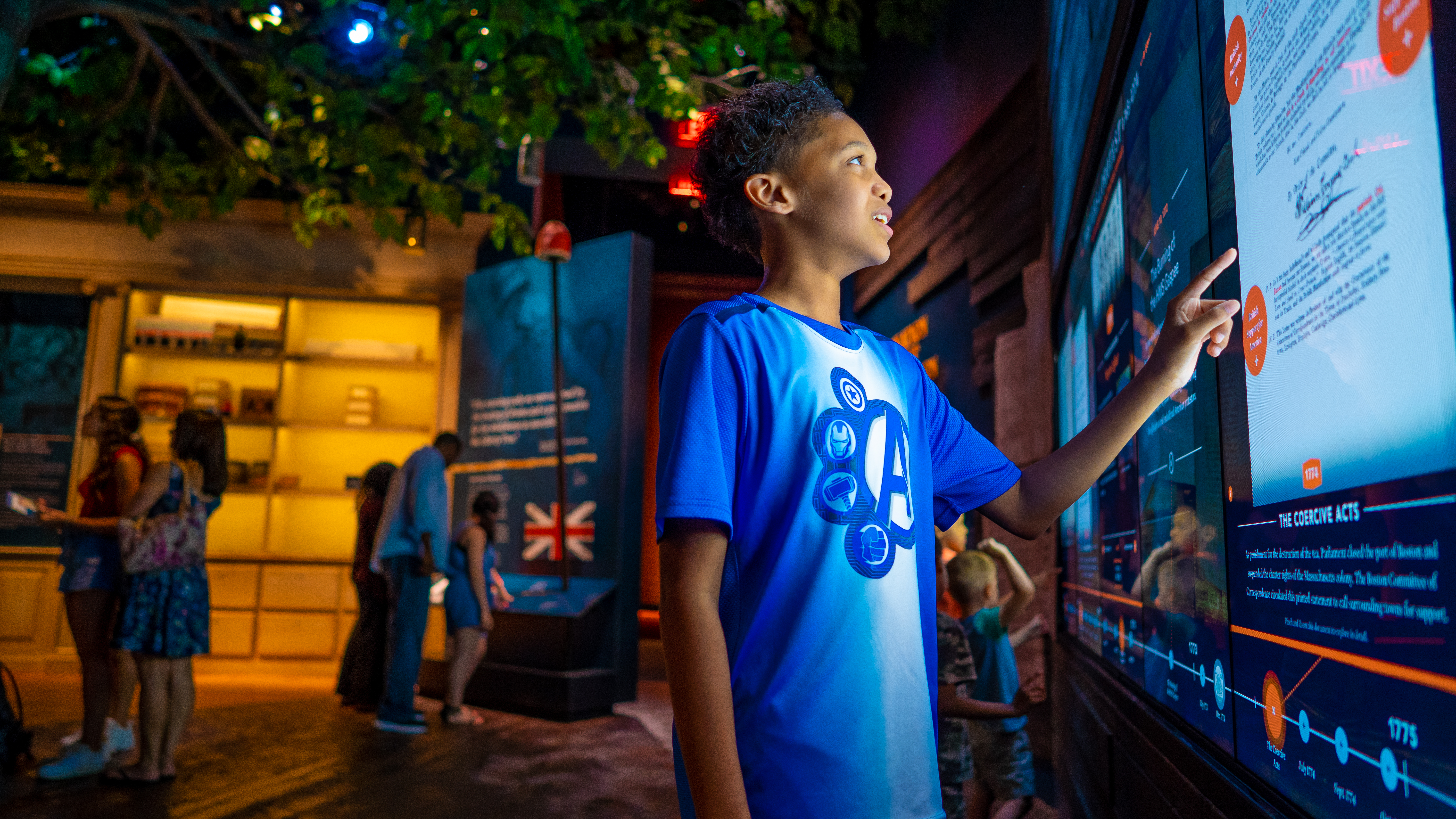 Kid in blue shirt interacts with Revolutionary War content touchscreen
