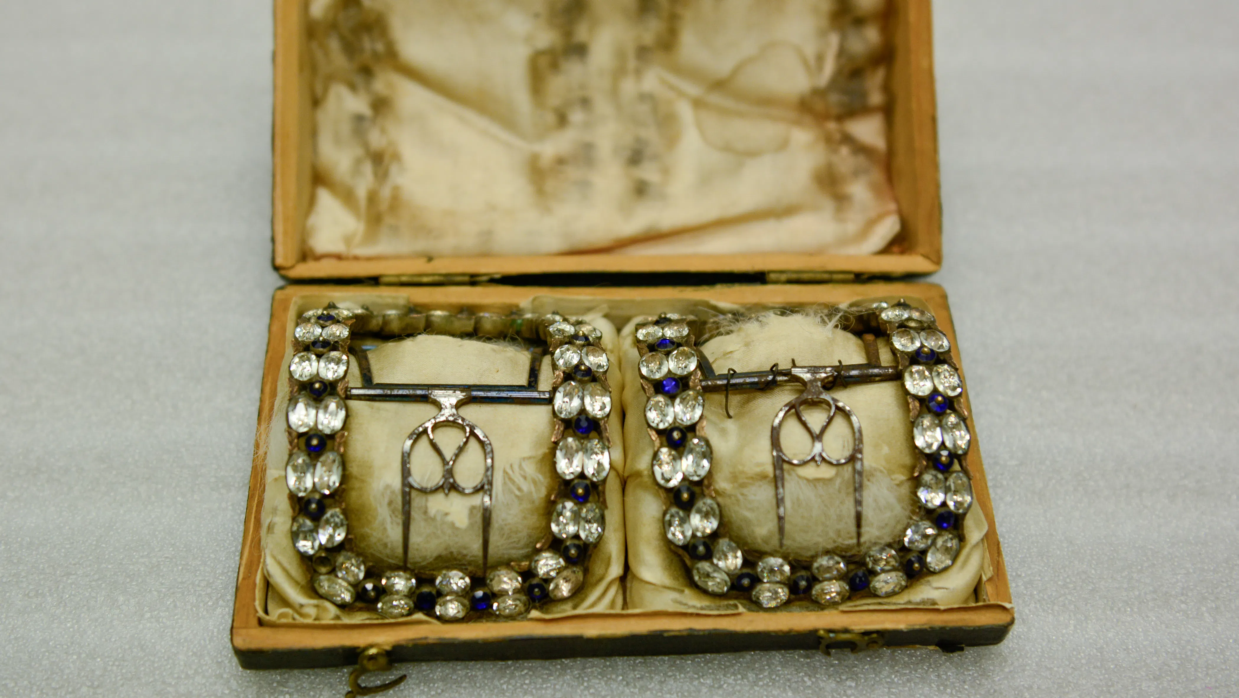 This image shows two diamond studded shoe buckles in a wooden case.