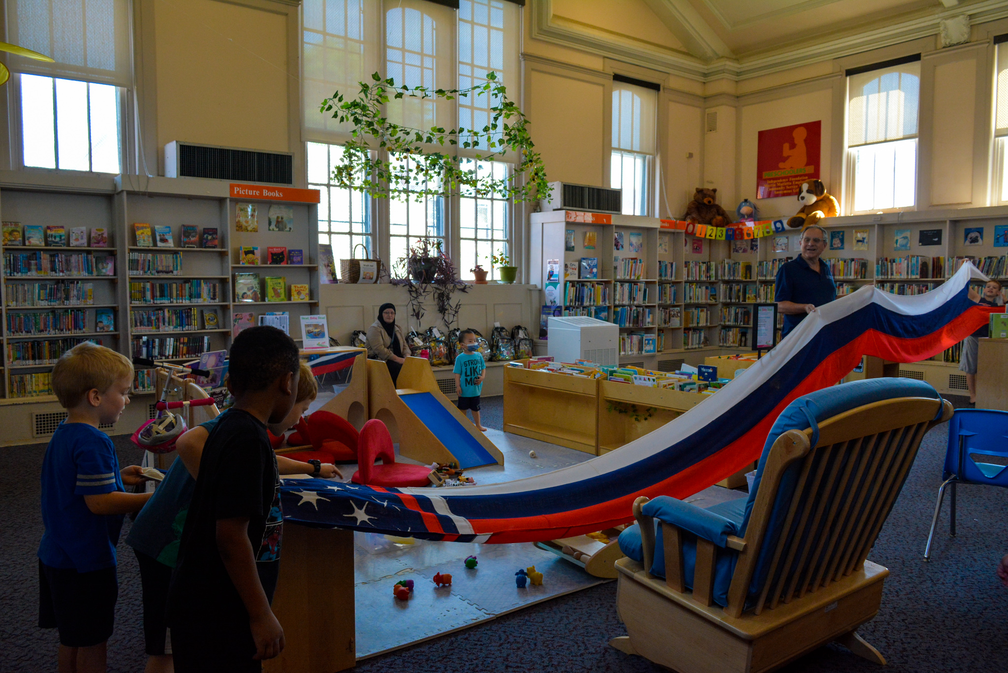 Young kids interact with a red, white, and blue flag