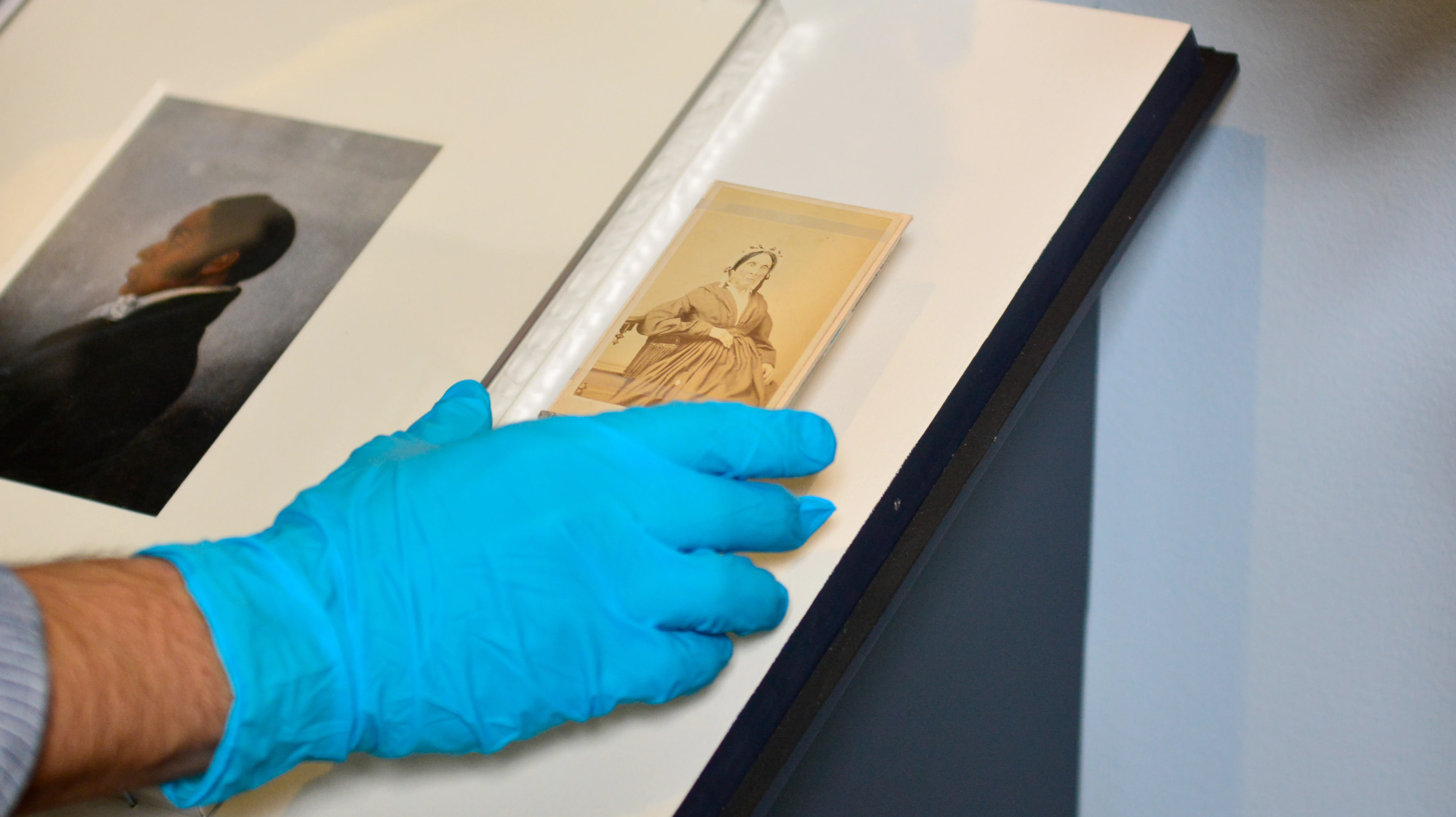 A museum curator places a photograph of Charlotte Vandine Forten in its case for display in Black Founders.