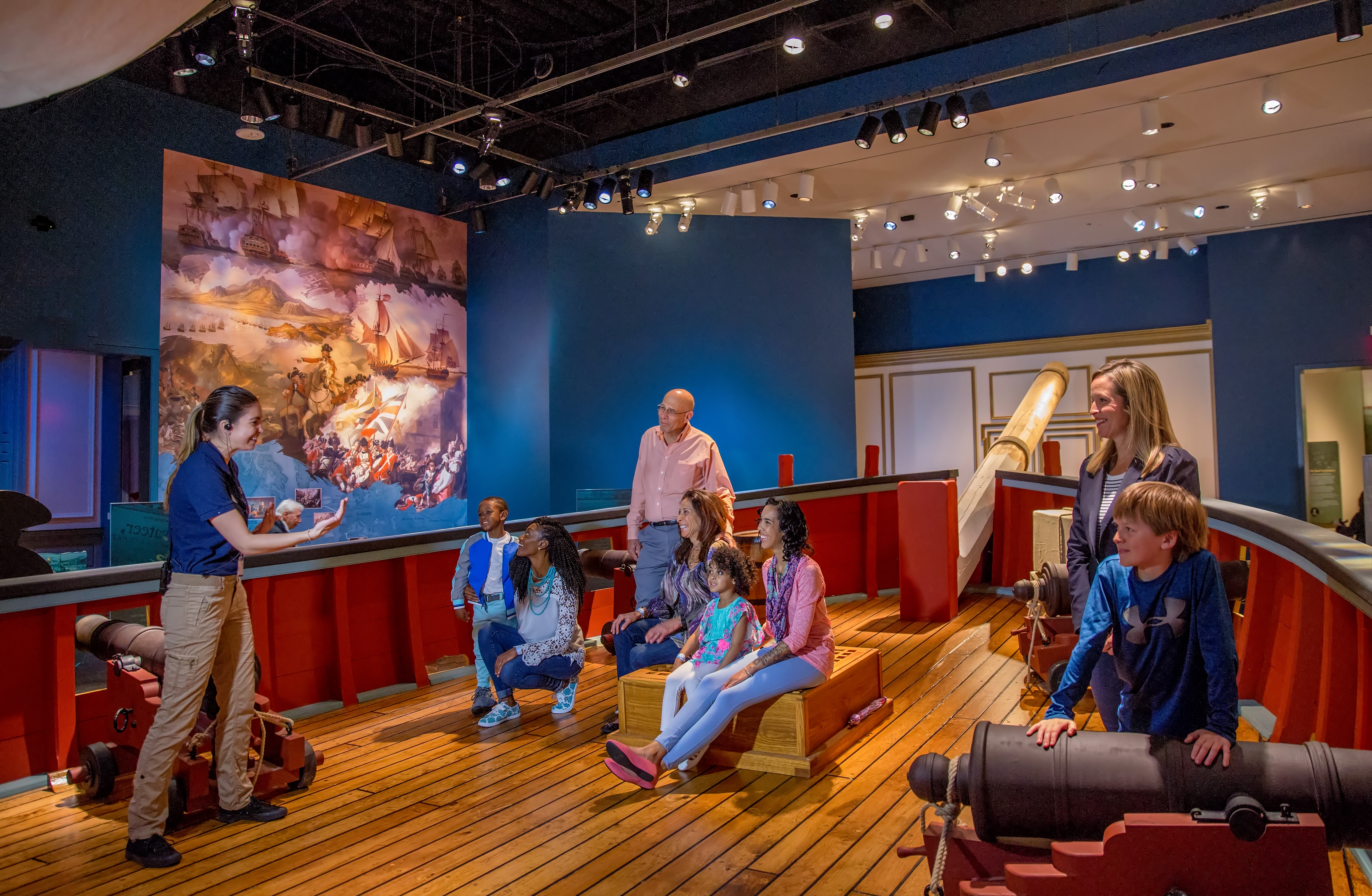 A visitor engagement associate educates families on the Privateer Ship in the galleries.
