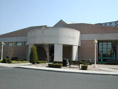The front facade of the William G. Rohrer Memorial Library in Haddon Township New Jersey features a brick facade with a cylinder stone entrance way.