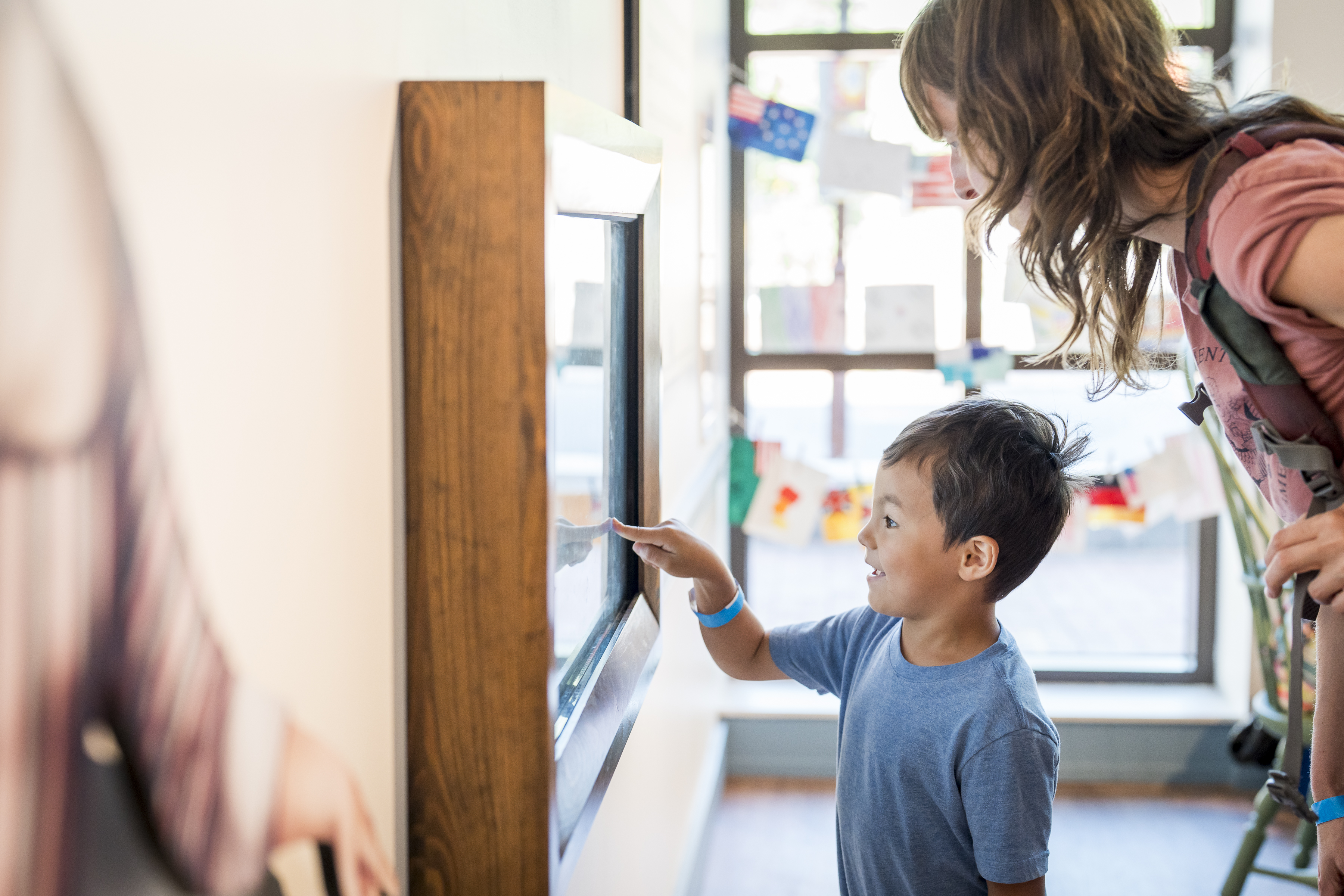 A child touches an interactive screen while an adult watches