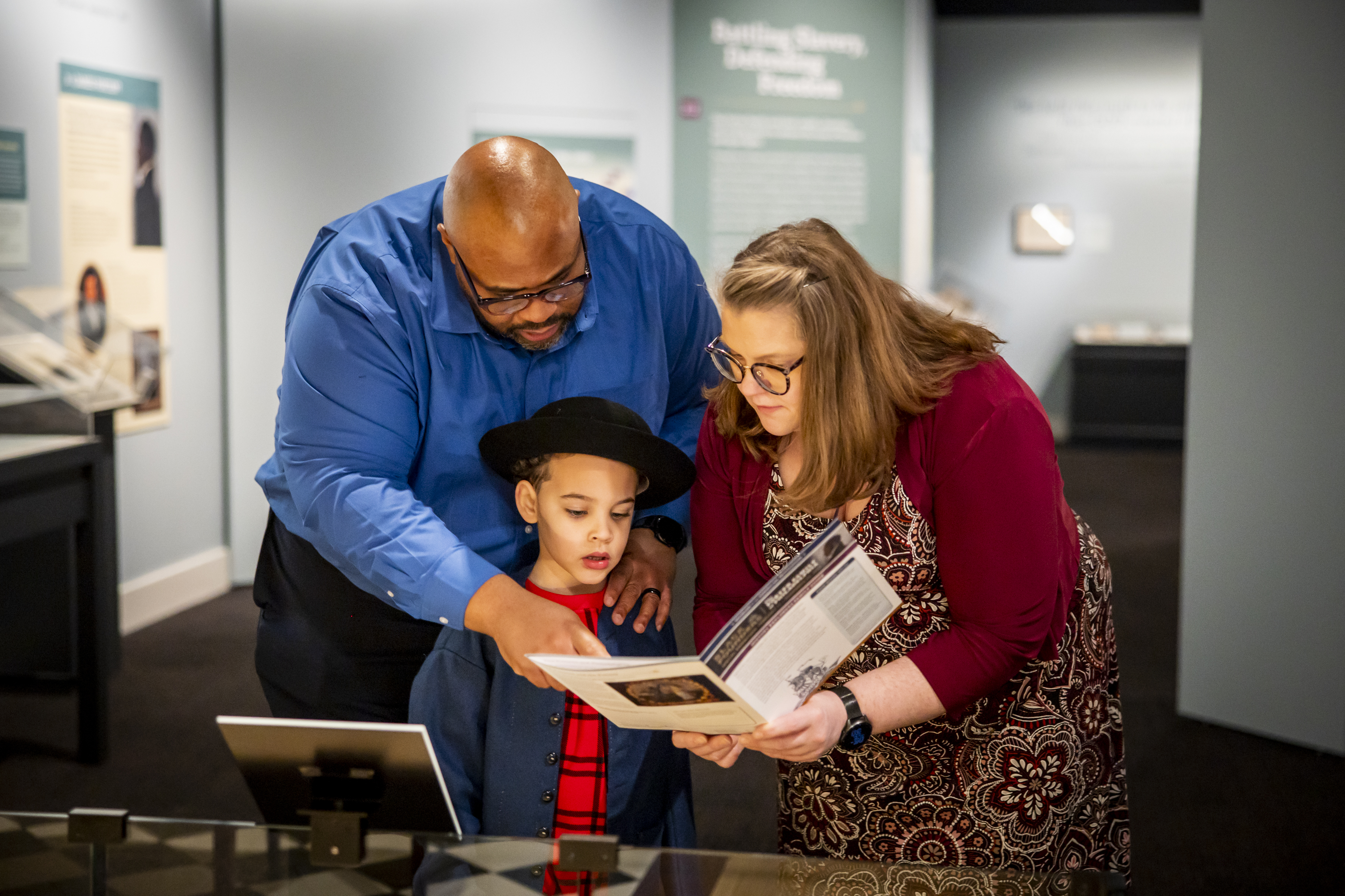 A family looks at the family guide activities in the Museum's Black Founders exhibit.