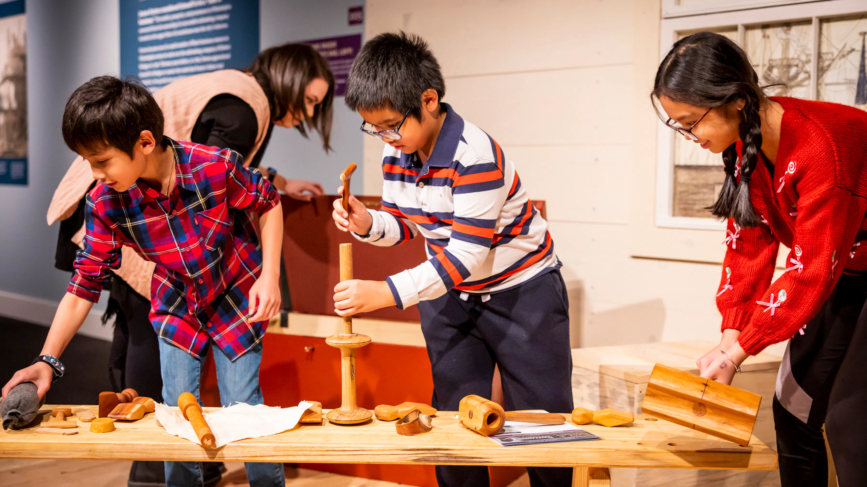 Three children use replica tools in a recreated sail loft in the Museum's Black Founders exhibit.