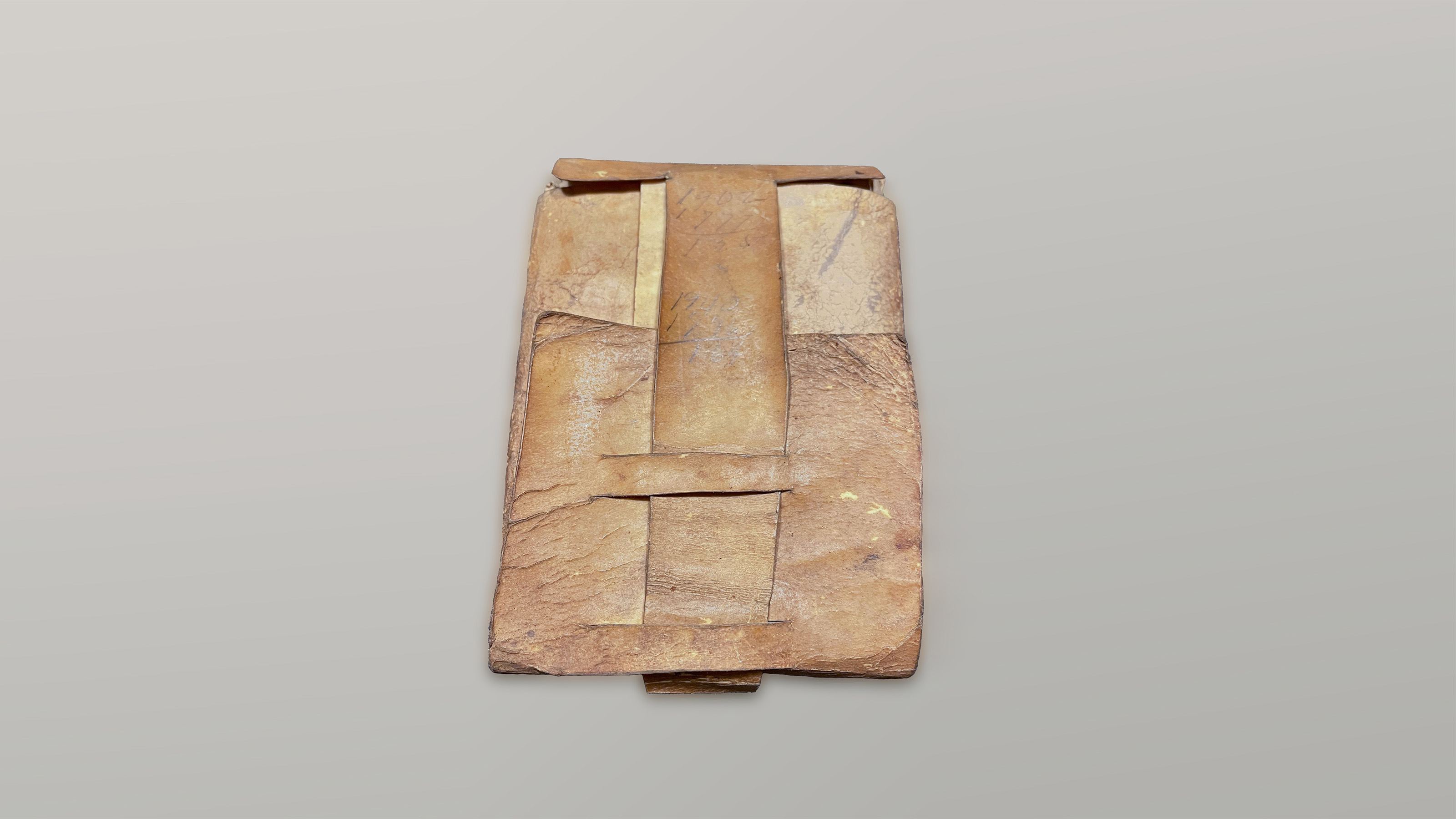 This image shows a brownish beige leather wallet closed with a long strap.