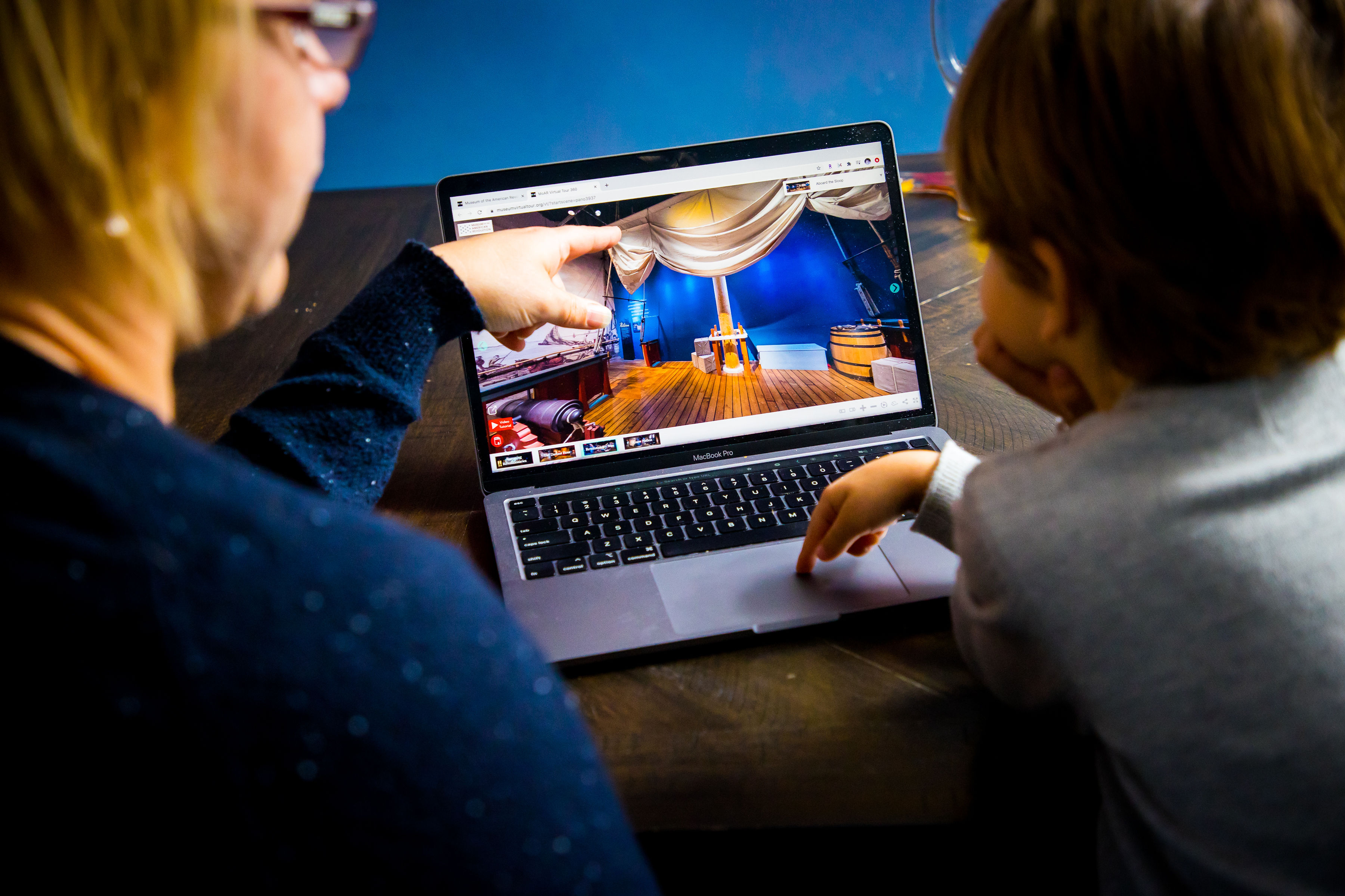 Child and adult browsing the virtual museum tour on their laptop